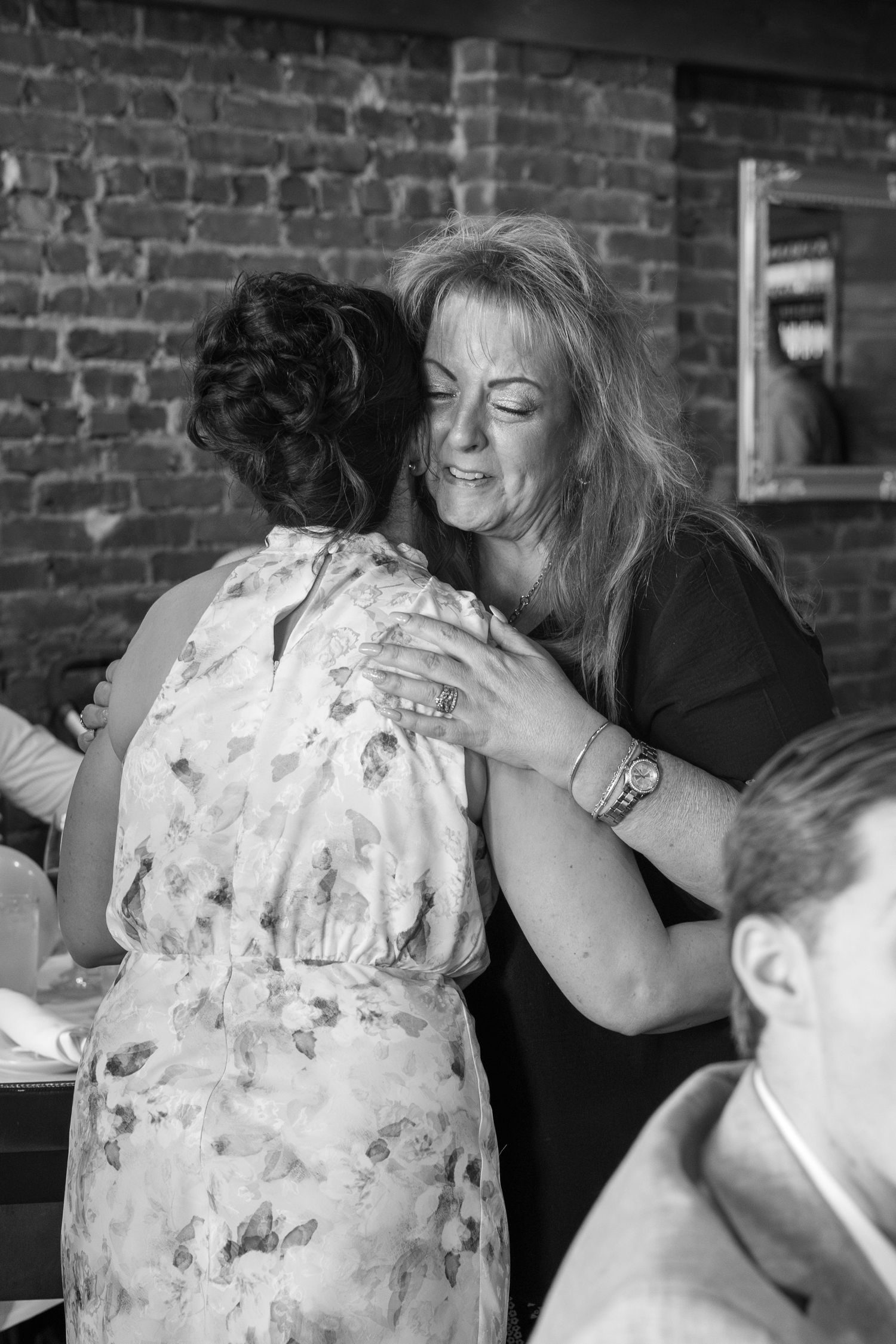 Two people sharing an emotional embrace at an indoor celebration.