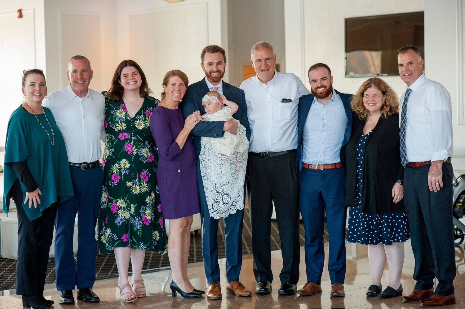 Extended family members pose together for a group photo in a bright indoor setting.