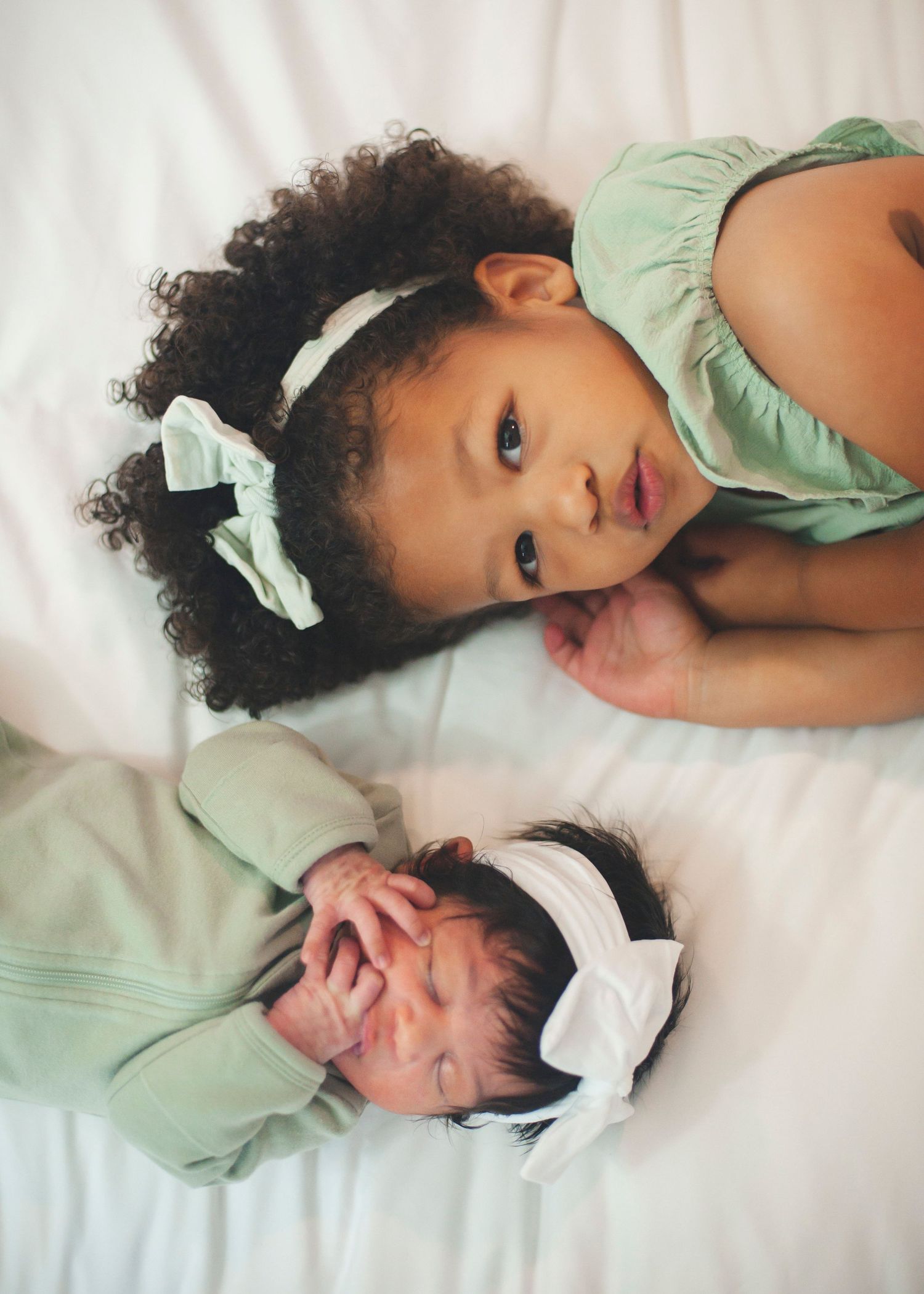 Photo series showing two siblings bonding on white bedding.