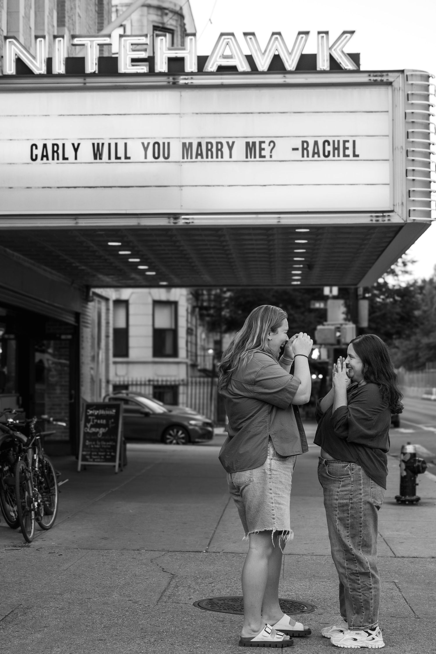 A black and white photo series showing a marriage proposal outside a theater with the words 'Will you marry me?' displayed.