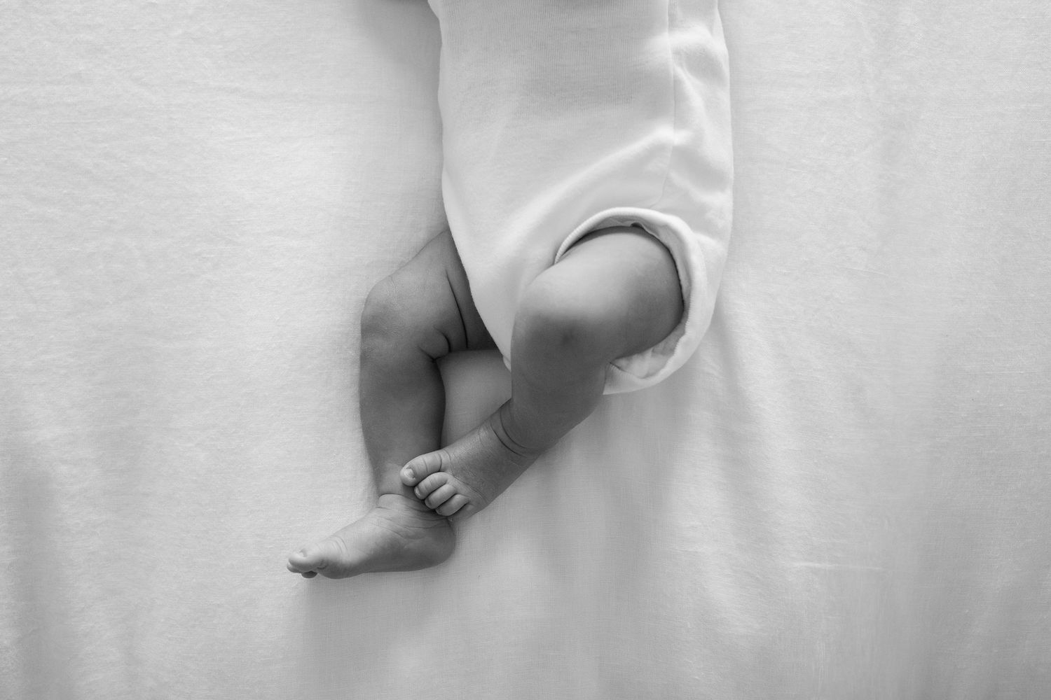 Minimalist black and white photo of sleeping baby against white background.