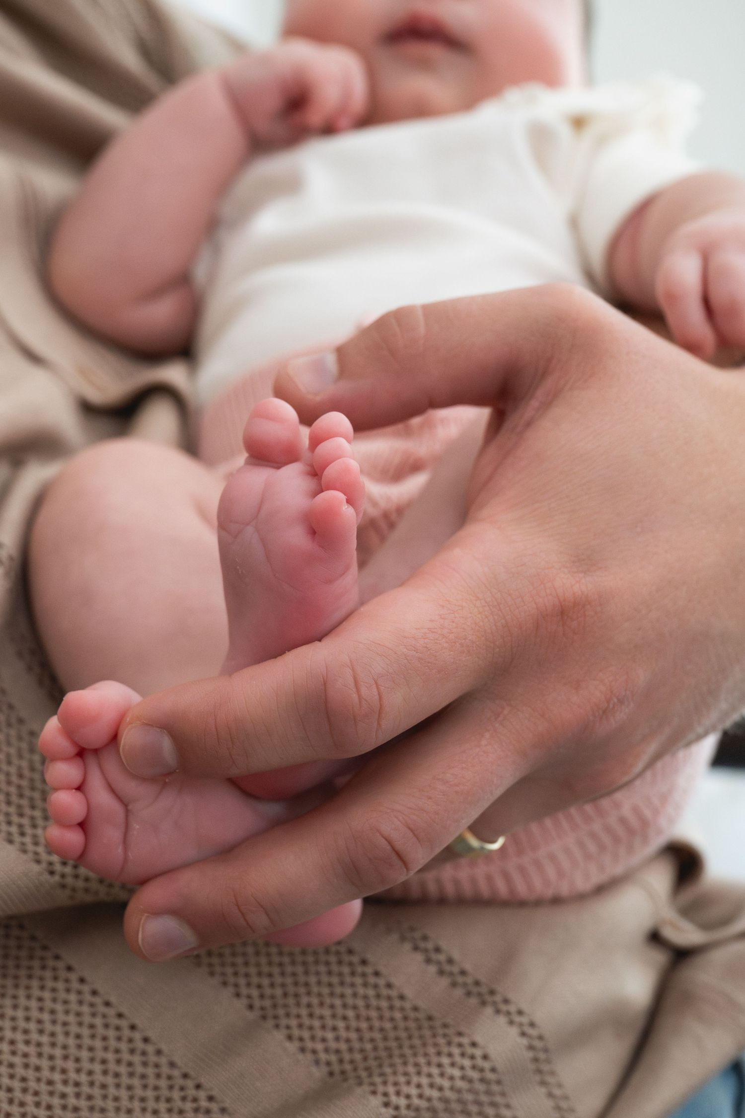 Close-up series of tiny baby feet being gently held by adult hands.