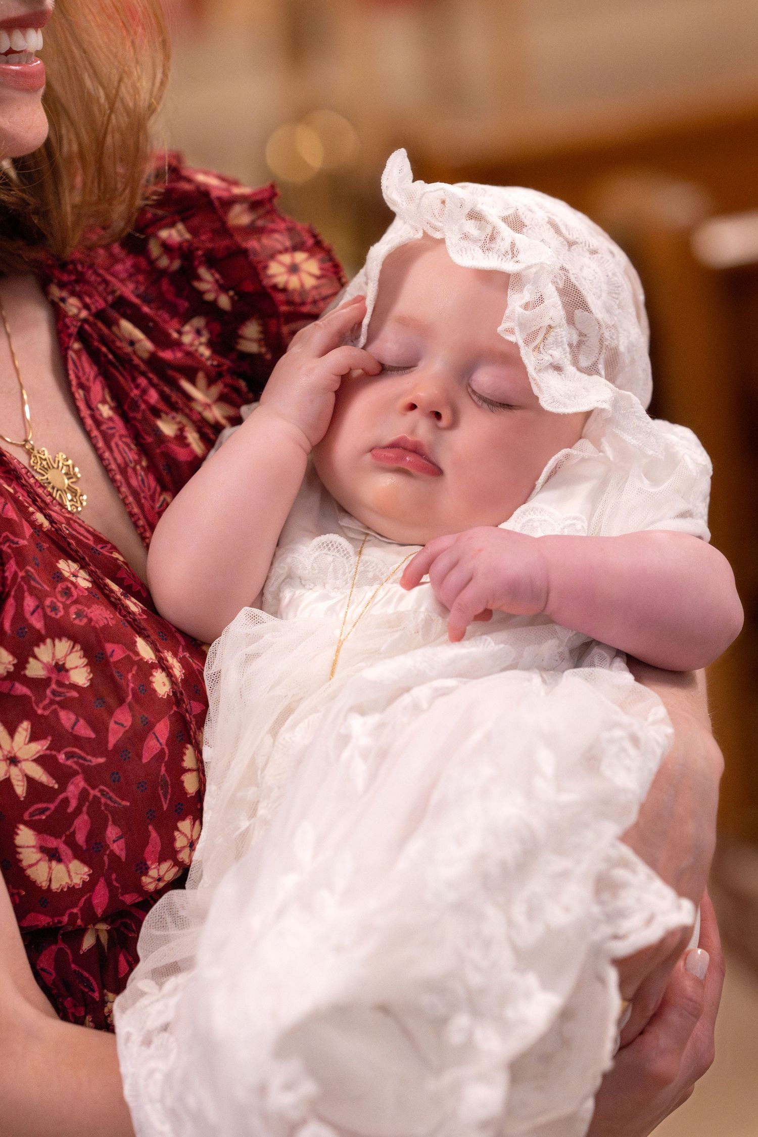 Baby wearing traditional white christening gown during religious ceremony.