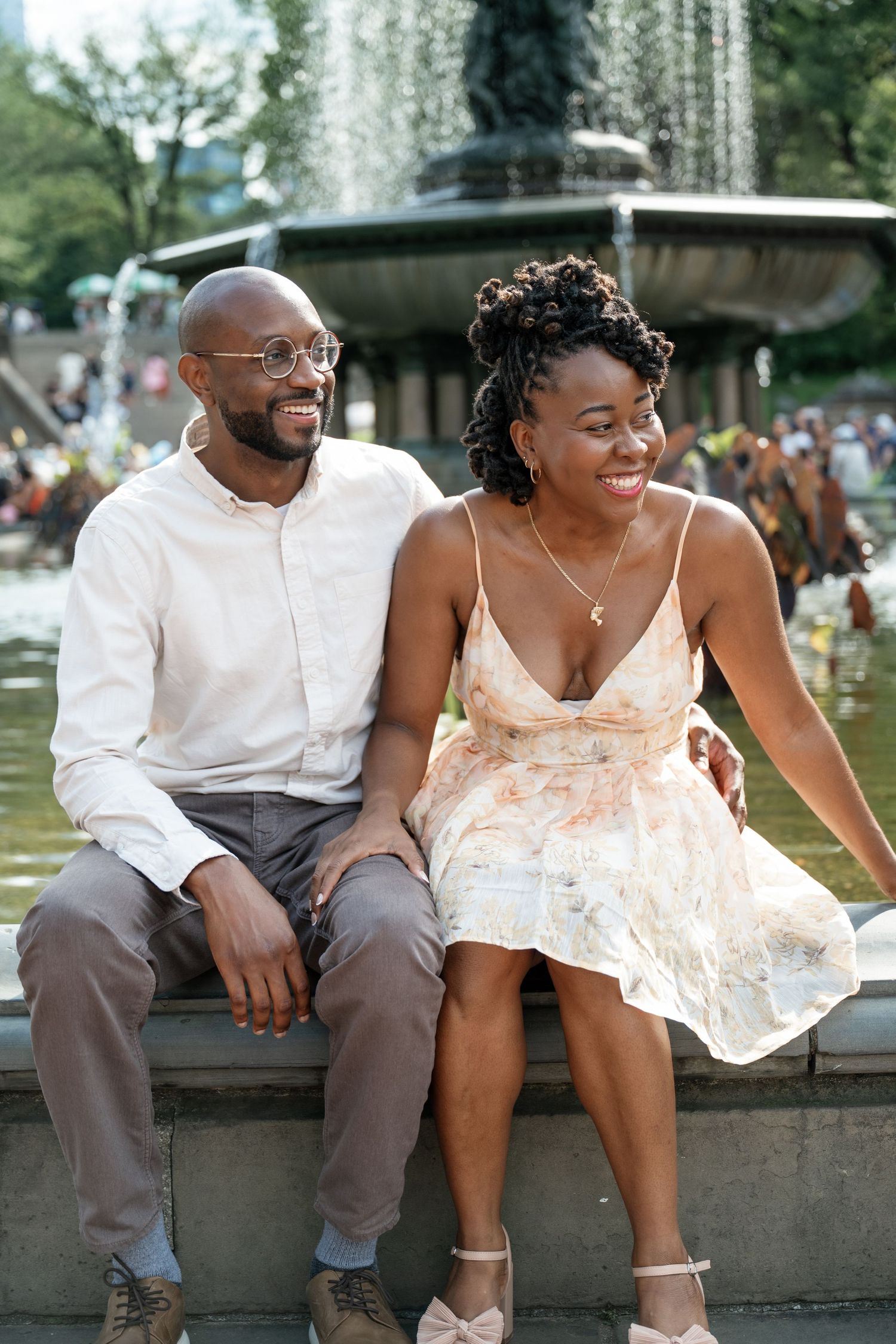 A couple sits together on stone steps in a romantic outdoor setting.