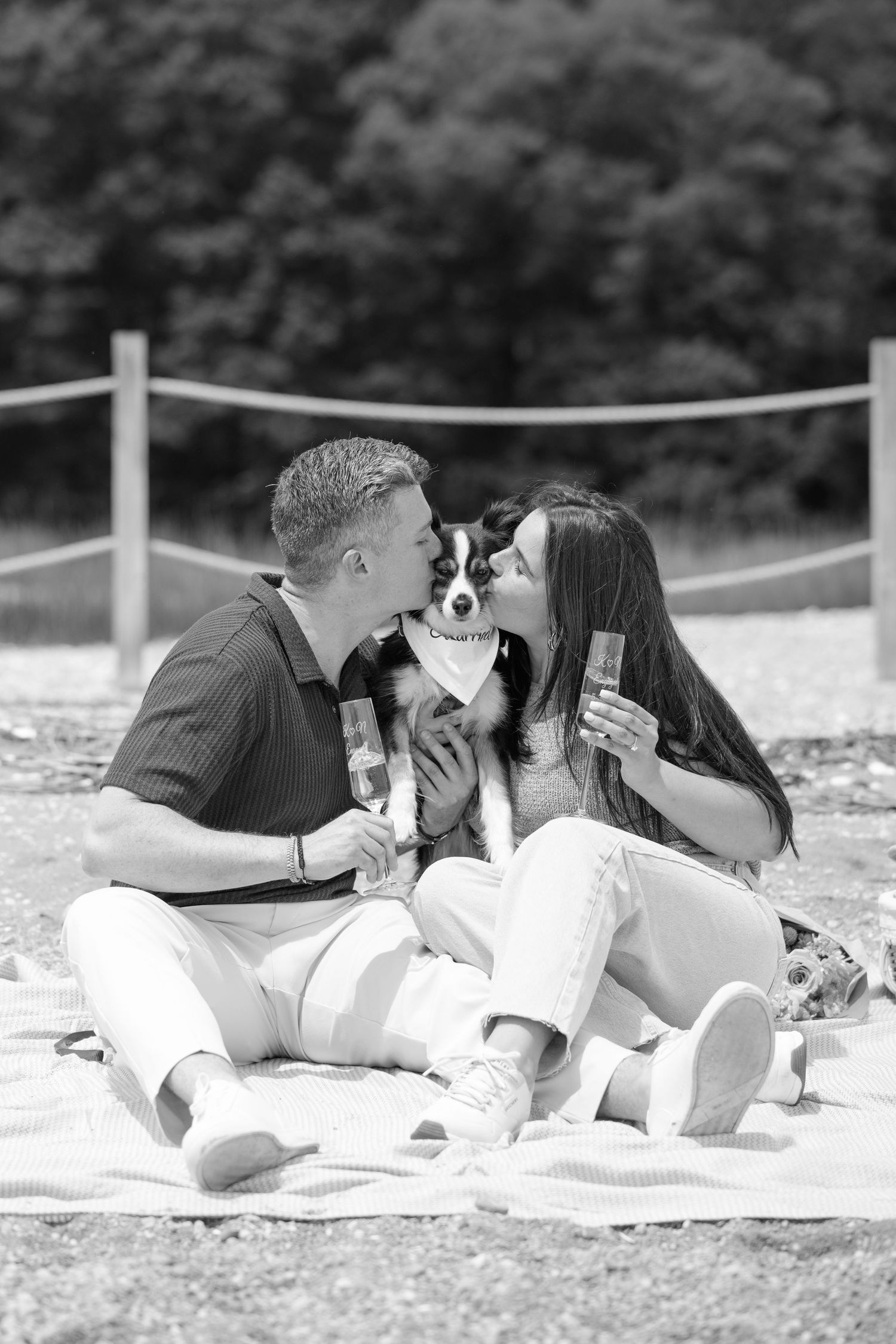 A couple lies on a blanket having a picnic while taking photos of each other in black and white.