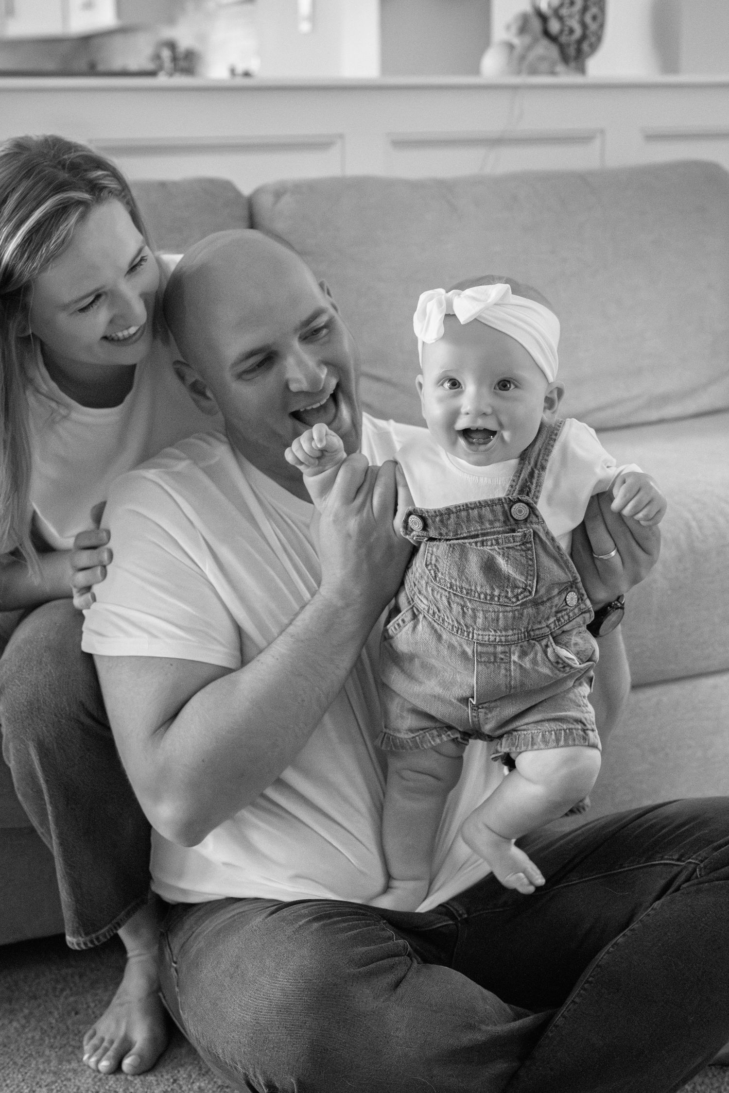 A joyful family moment captured in black and white as they share laughter together on a couch.