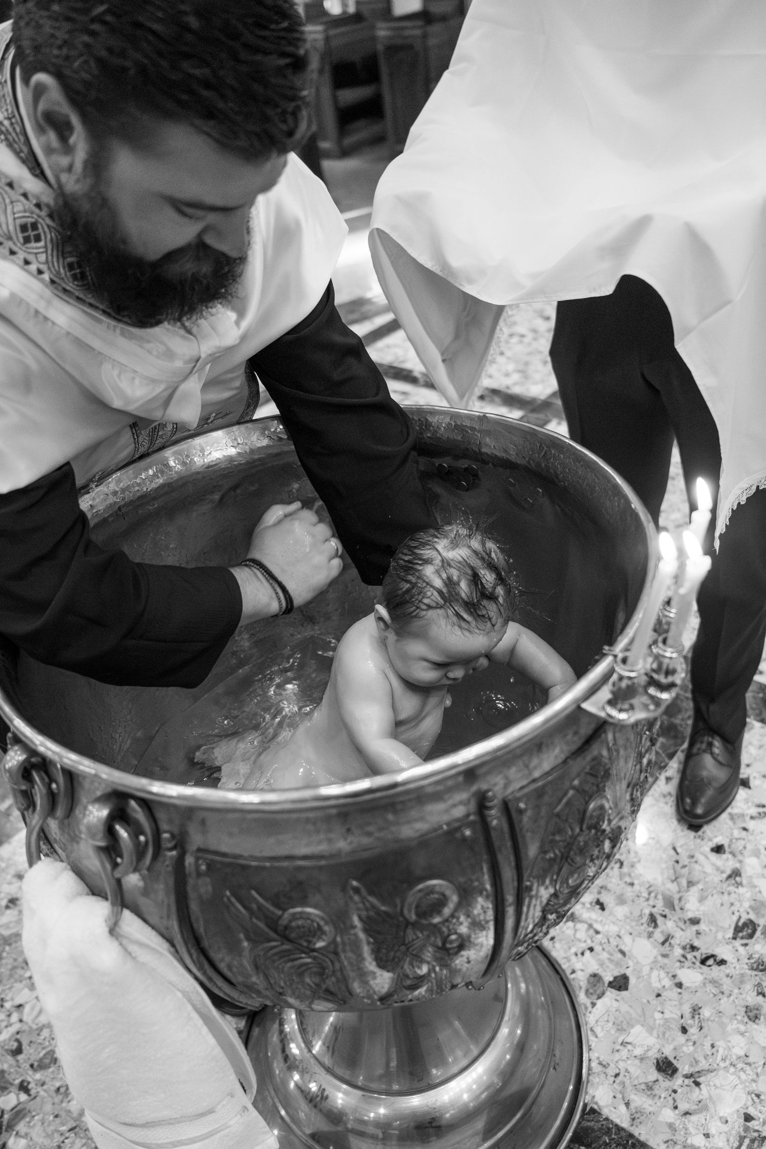 A close-up sequence showing hands performing a baptism ritual by pouring water in a church baptismal font.
