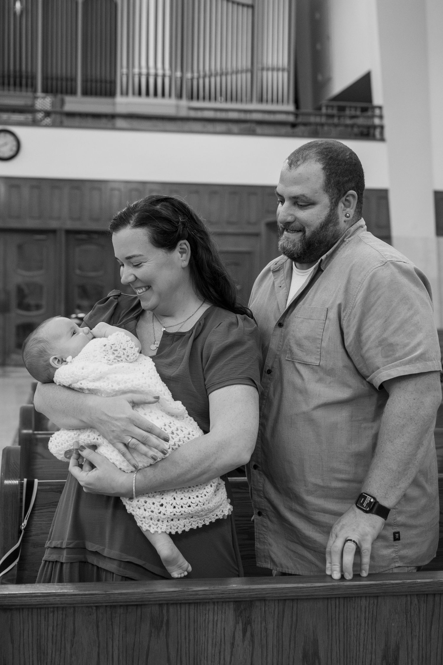 A family shares joyful moments with their baby in a church setting.