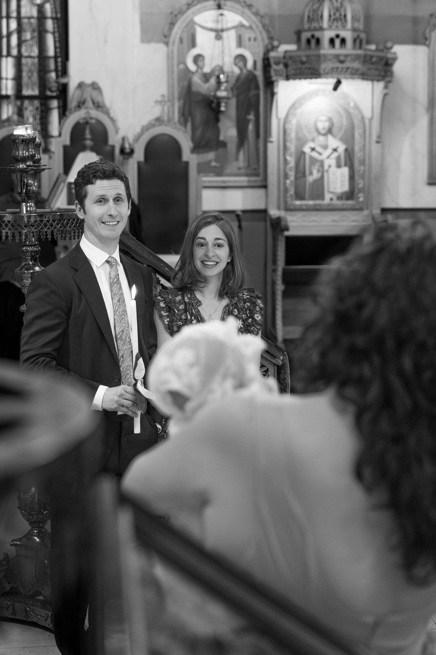 Guests observe a special moment during a church ceremony with ornate religious artwork in background.