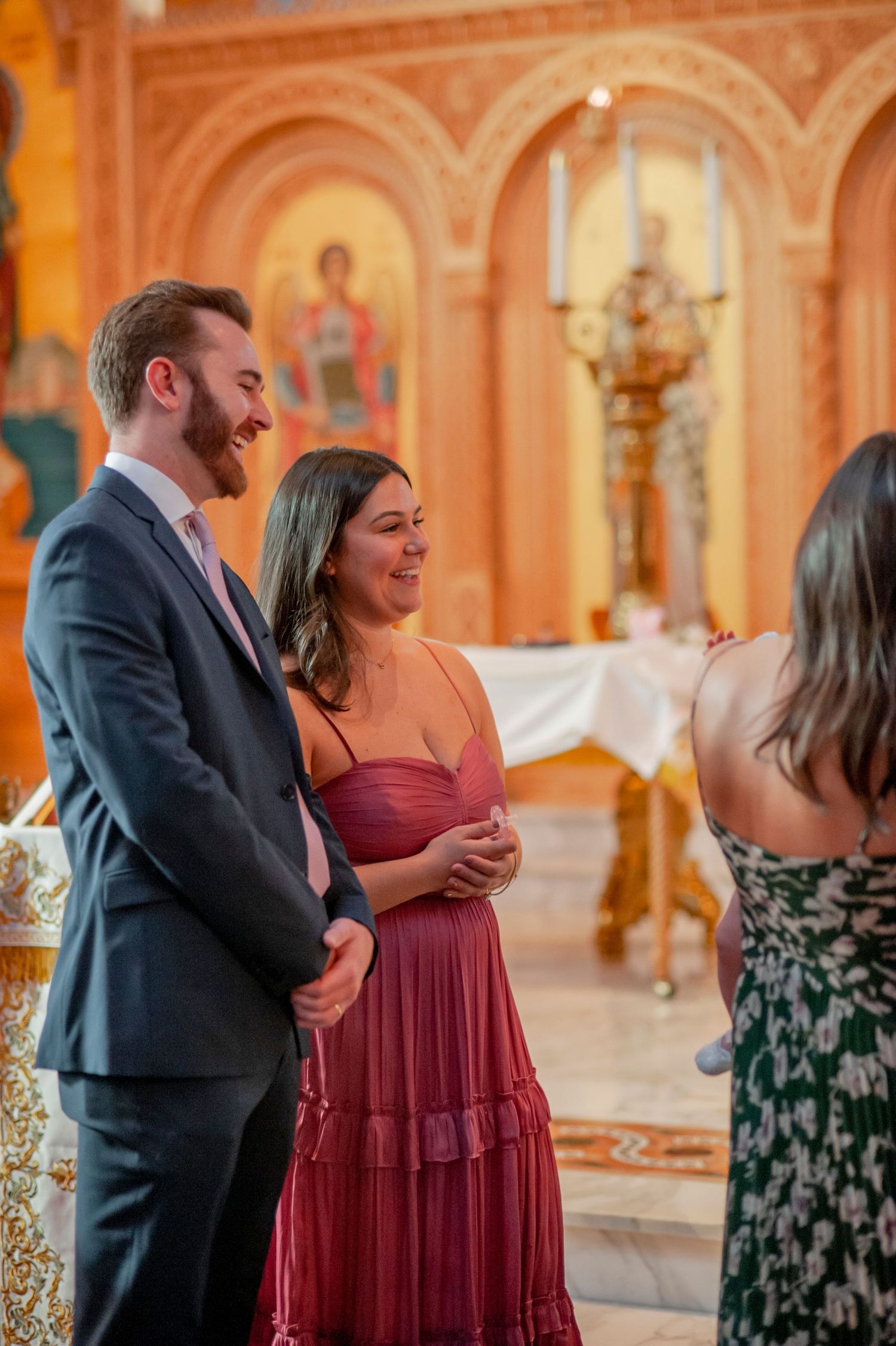 A couple dances together in an elegant ballroom with ornate architecture and warm lighting.