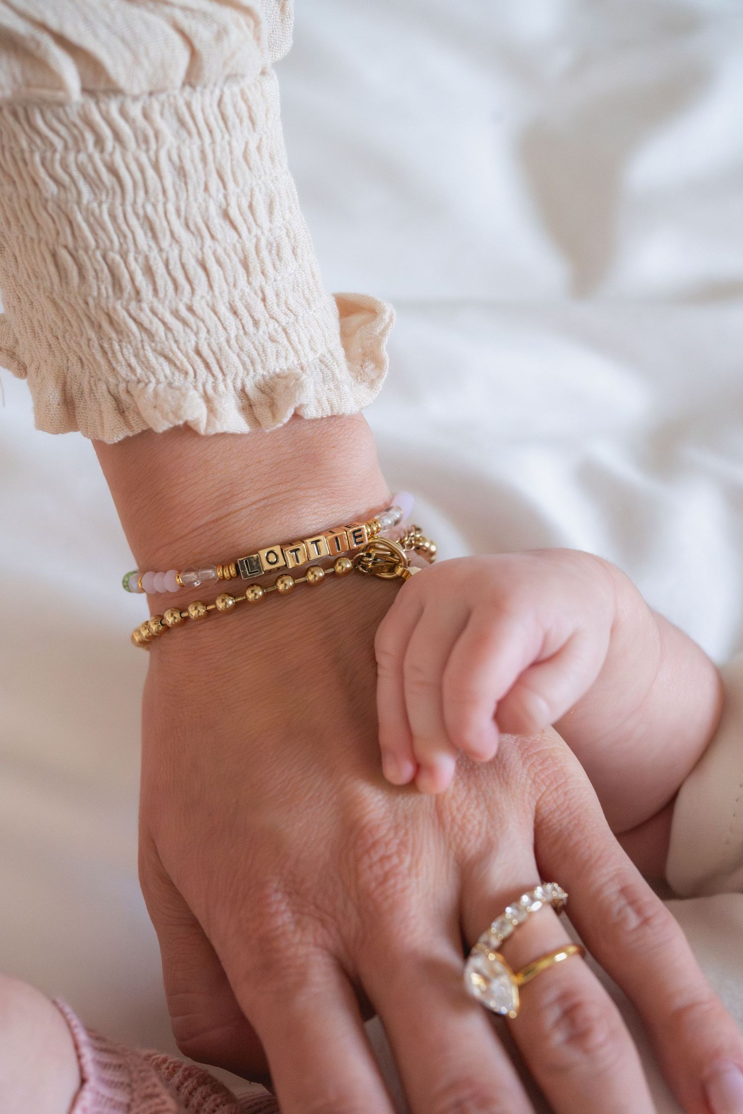 Close-up detail shots of infant and adult hands with jewelry.