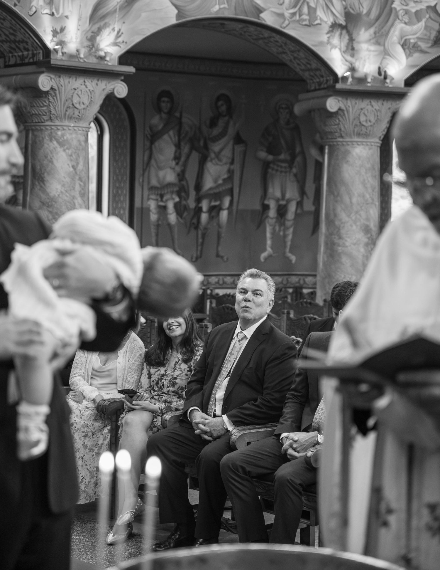 Black and white photo of guests seated in an ornate church during a baptism ceremony.