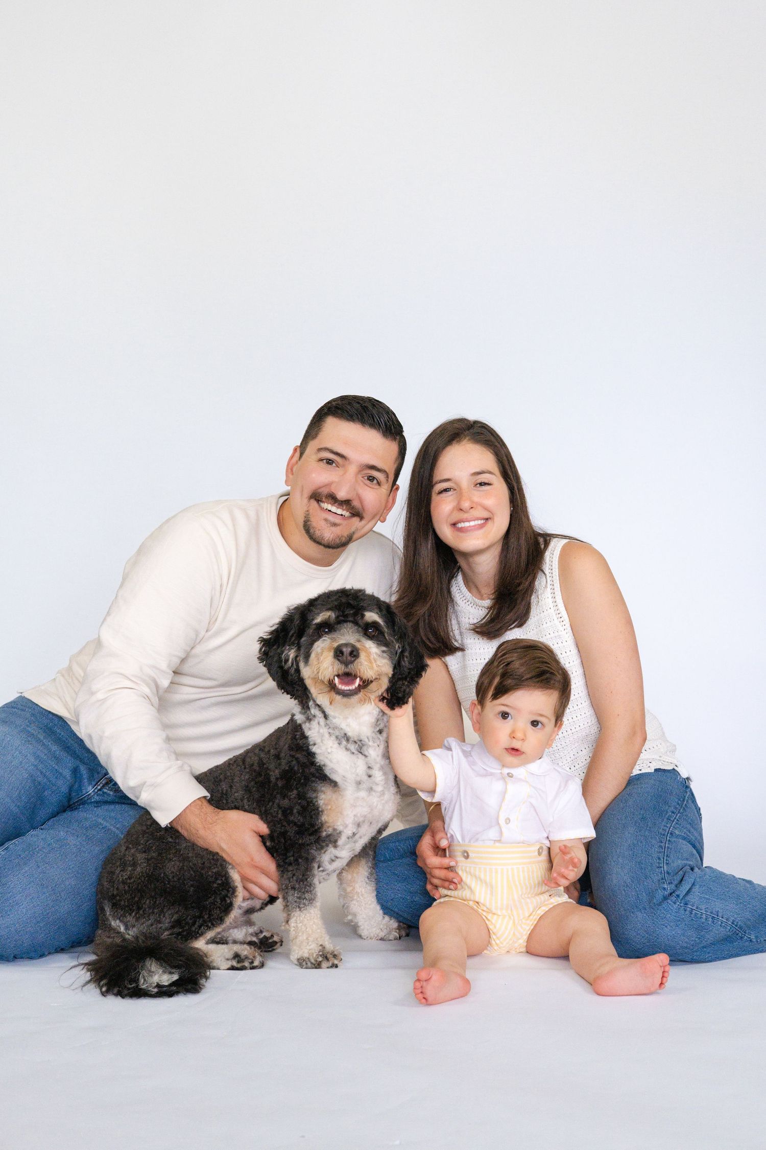 Family portrait with dog on white background showing loving connection.