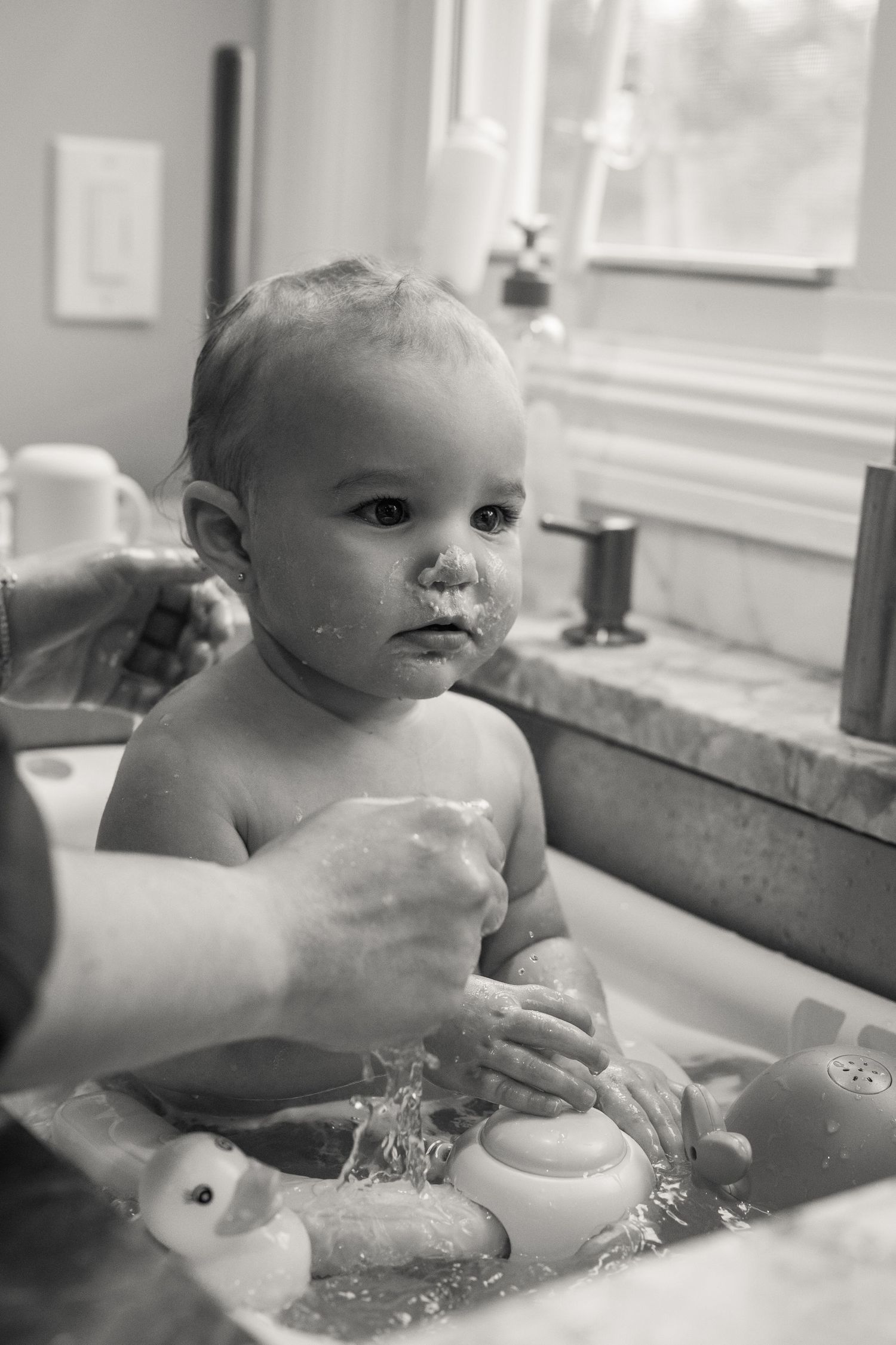 Baby splashing and playing in a bathtub filled with soapy water.
