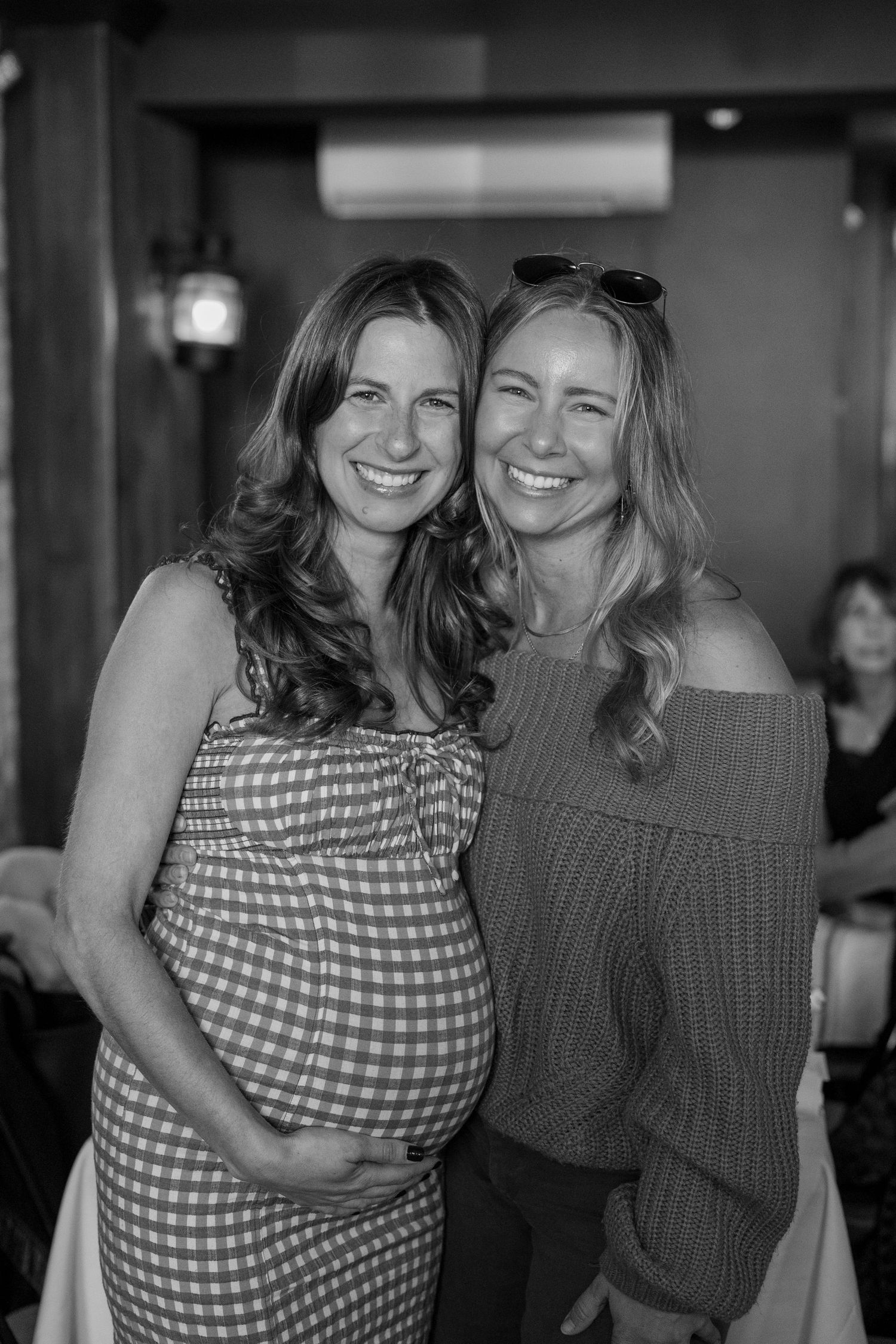 Two friends embracing and laughing together in a casual restaurant setting.