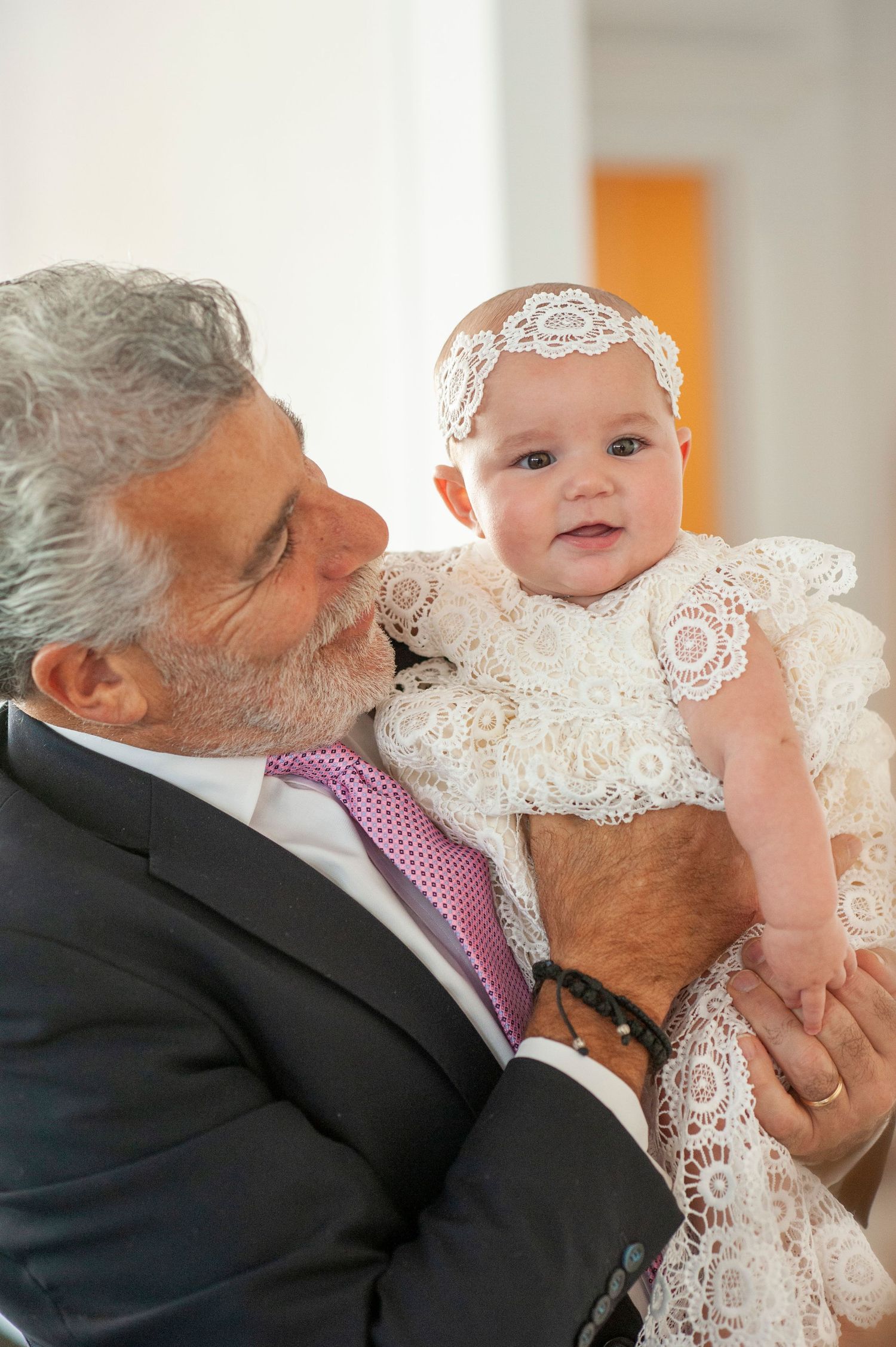 A tender moment during a christening ceremony with a baby in white lace dress.