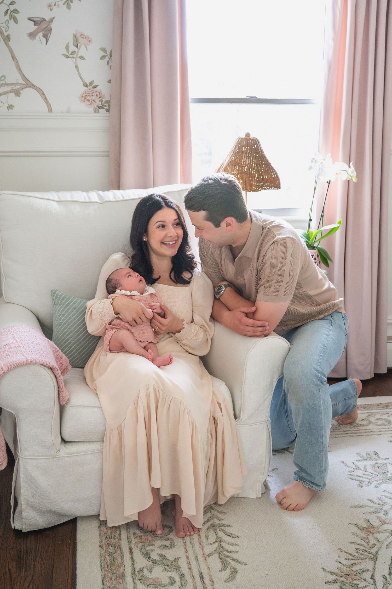 Series of intimate family moments on a white couch with floral rug and pink curtains.