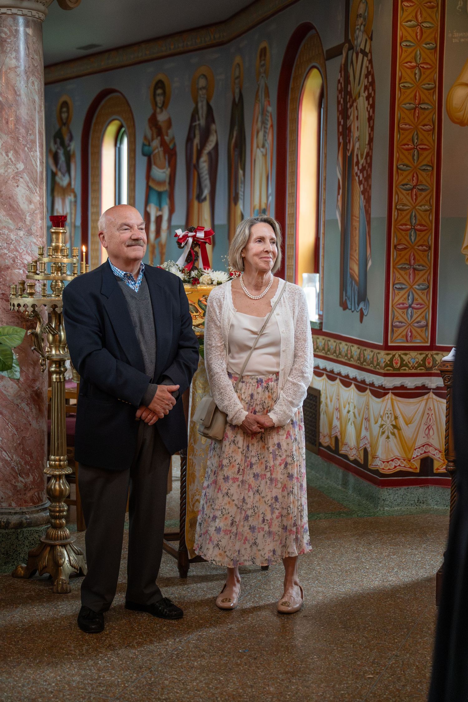 Couple standing together in ornate church with decorated walls and arched windows during wedding ceremony.