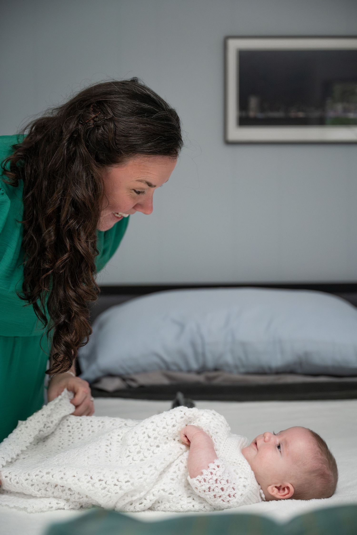 A sweet interaction between caregiver and infant on a bed with white linens.