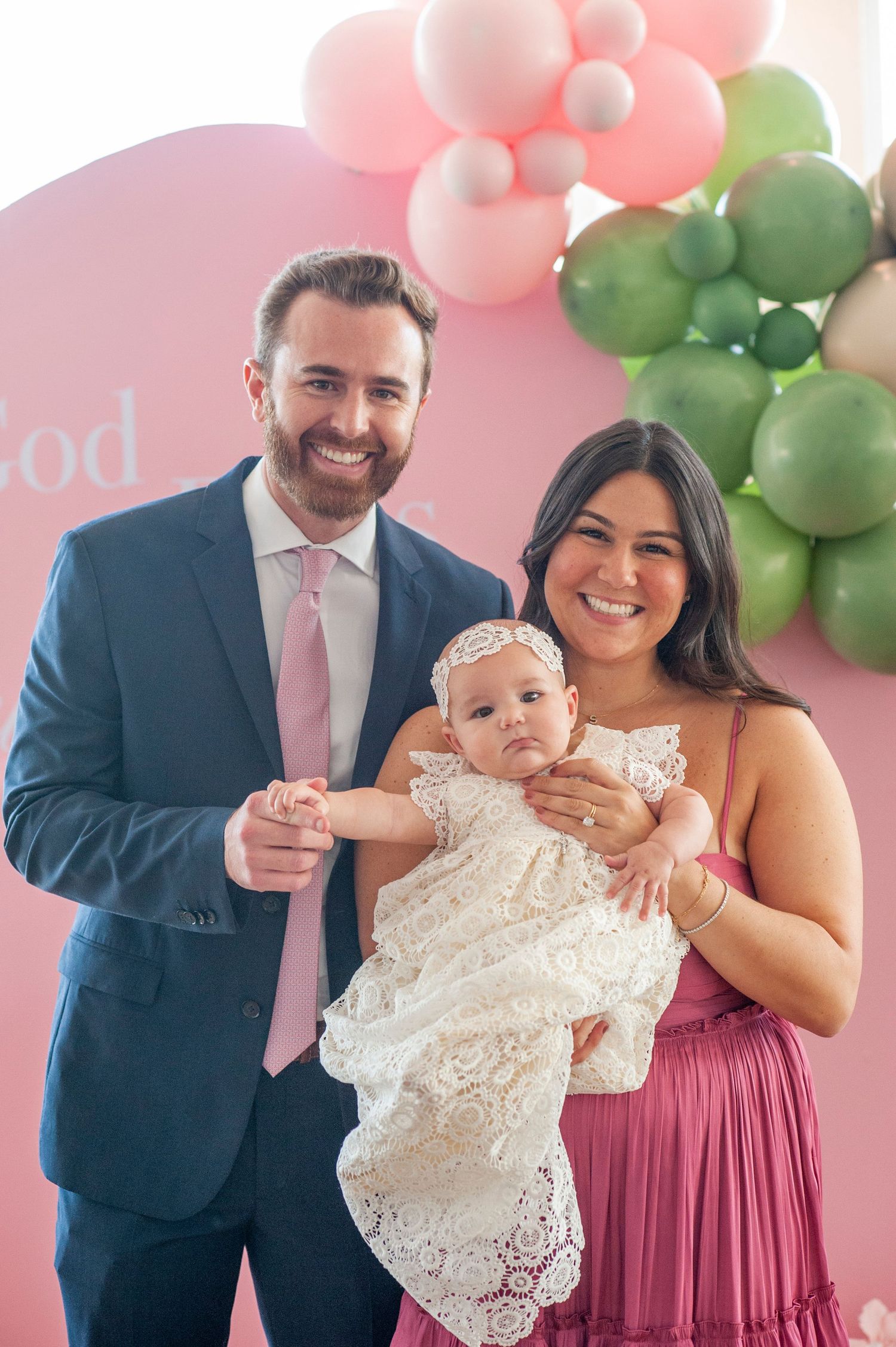 A christening celebration setup with pink and green balloon arch decorations.