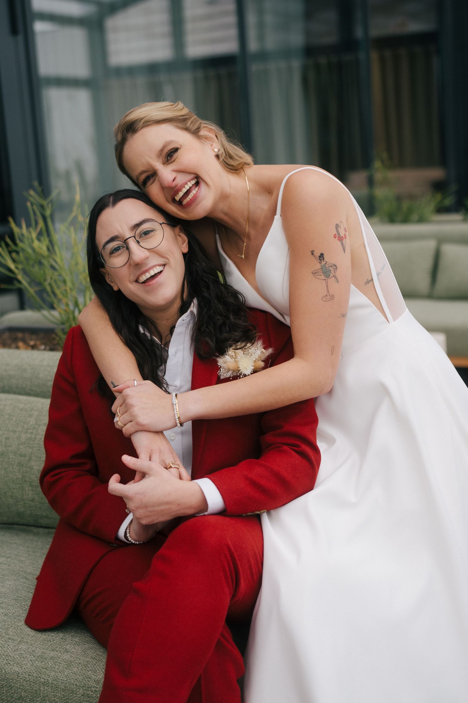 Wedding couple in red and white outfits sharing joyful moments outdoors.