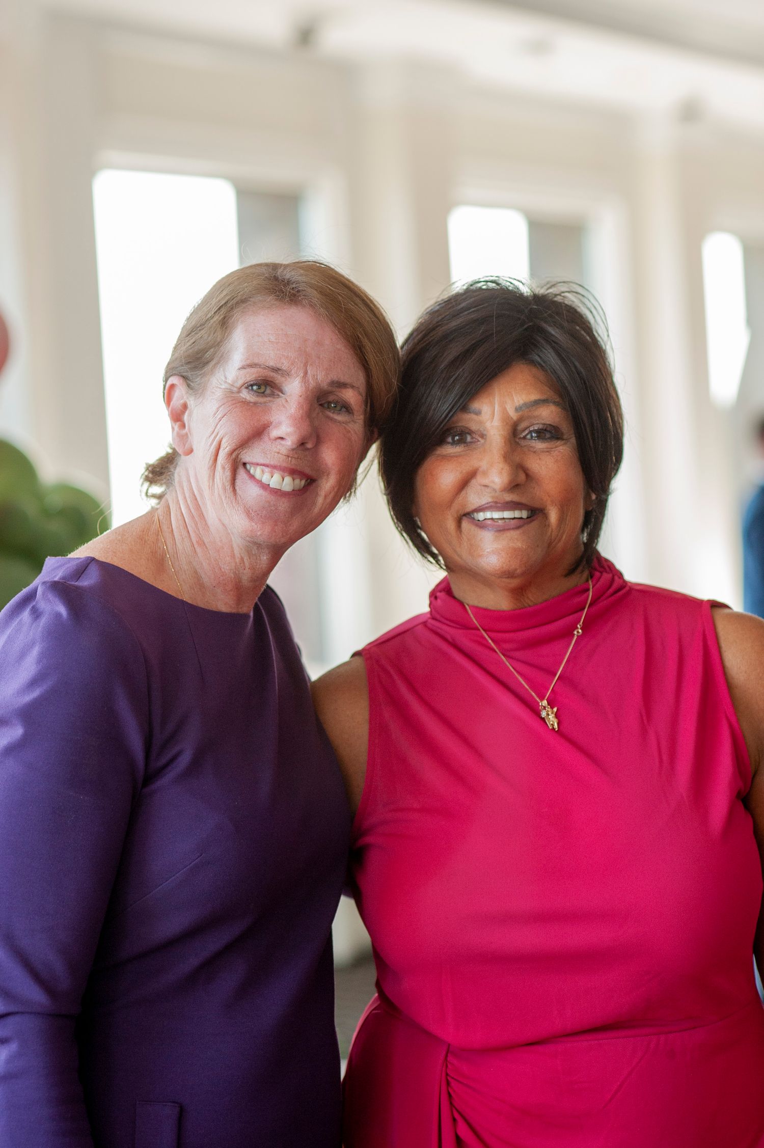 Two people in purple and pink tops smile warmly together in a series of casual portrait photos.