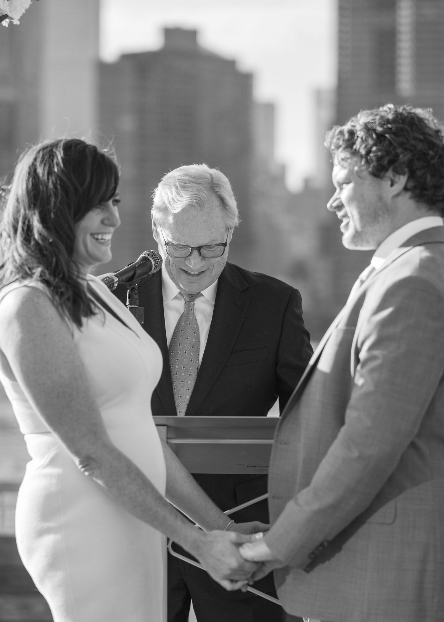 A black and white wedding ceremony photo showing multiple candid moments between couples in formal attire.
