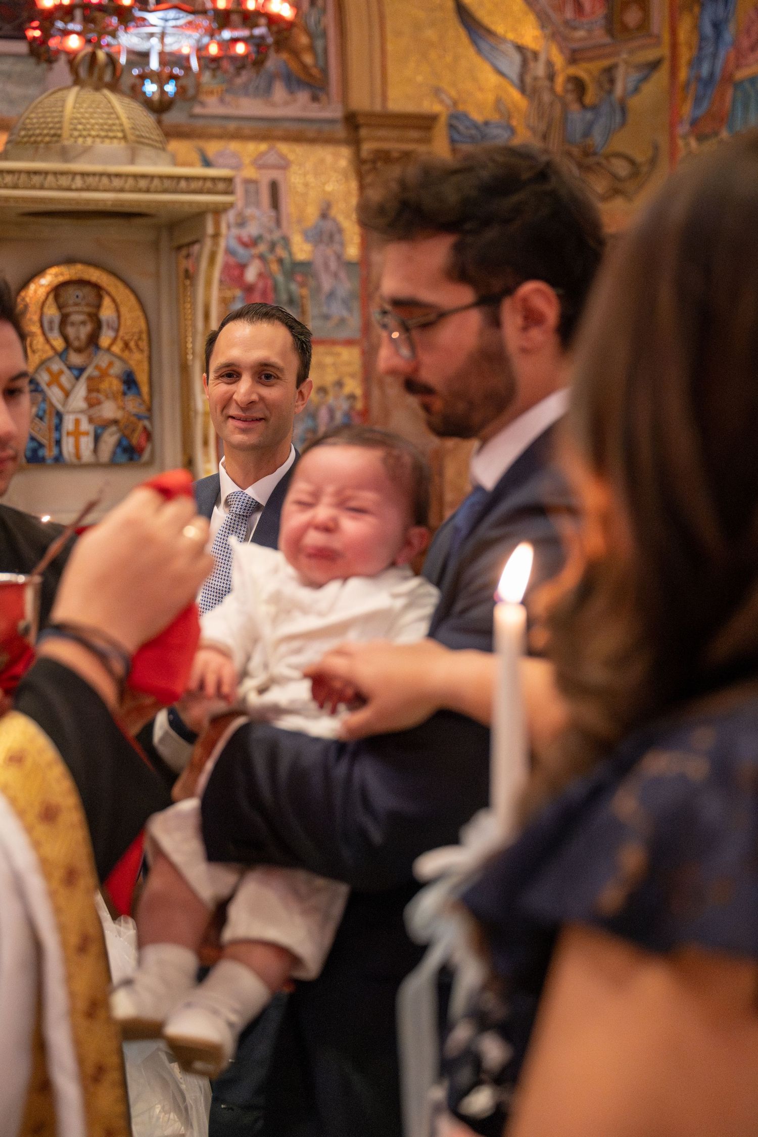 An emotional moment during a baptism ceremony inside a church with ornate religious artwork.