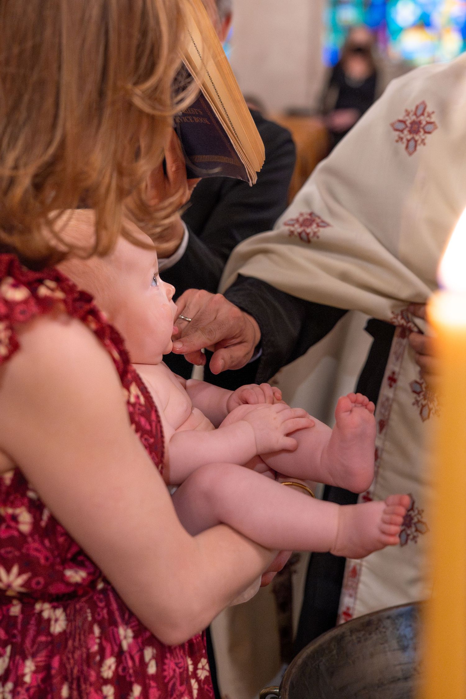 Close-up of an infant being prepared for a baptism ceremony in traditional white garments.