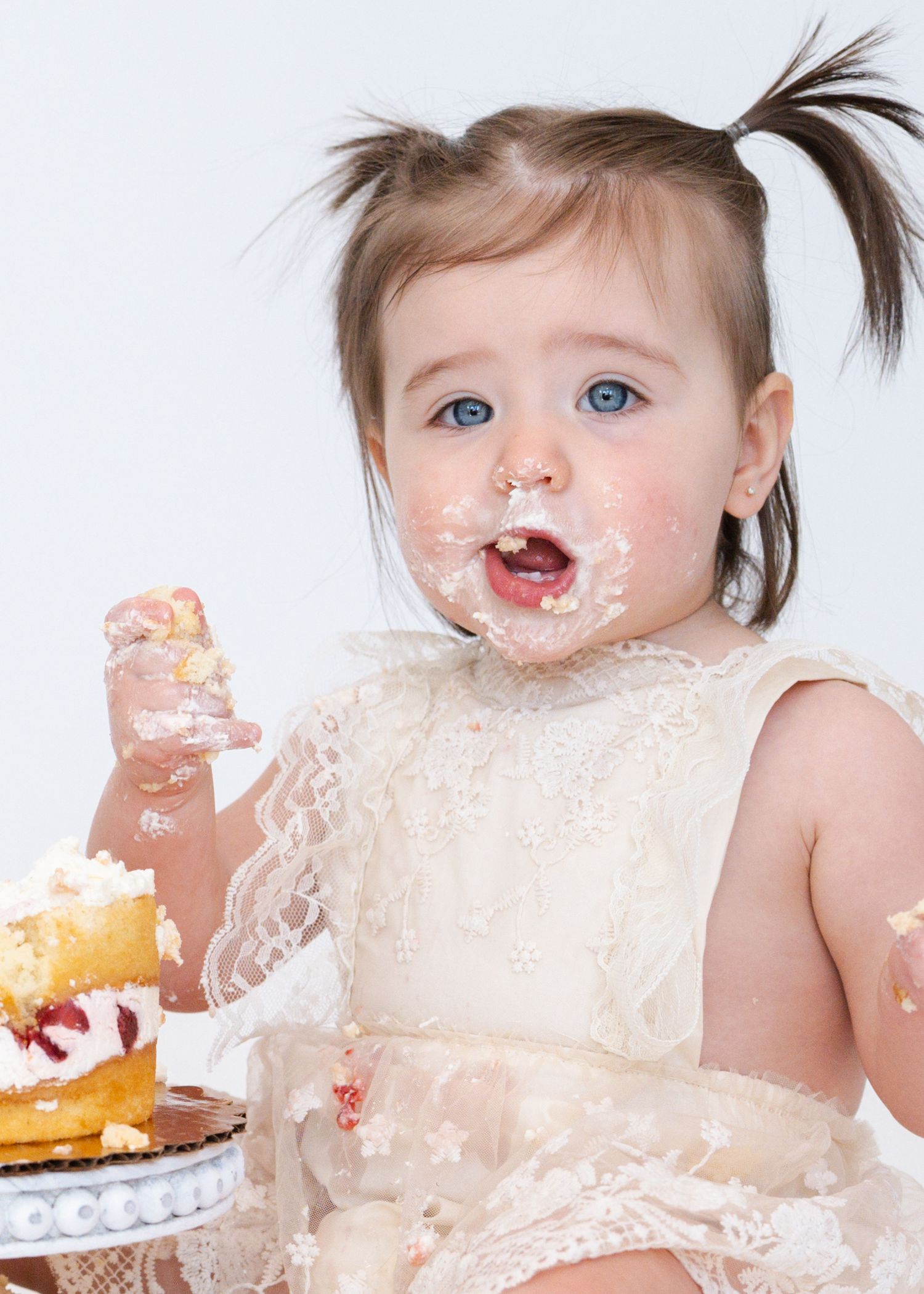Messy baby enjoying cake smash photoshoot with frosting all over face.