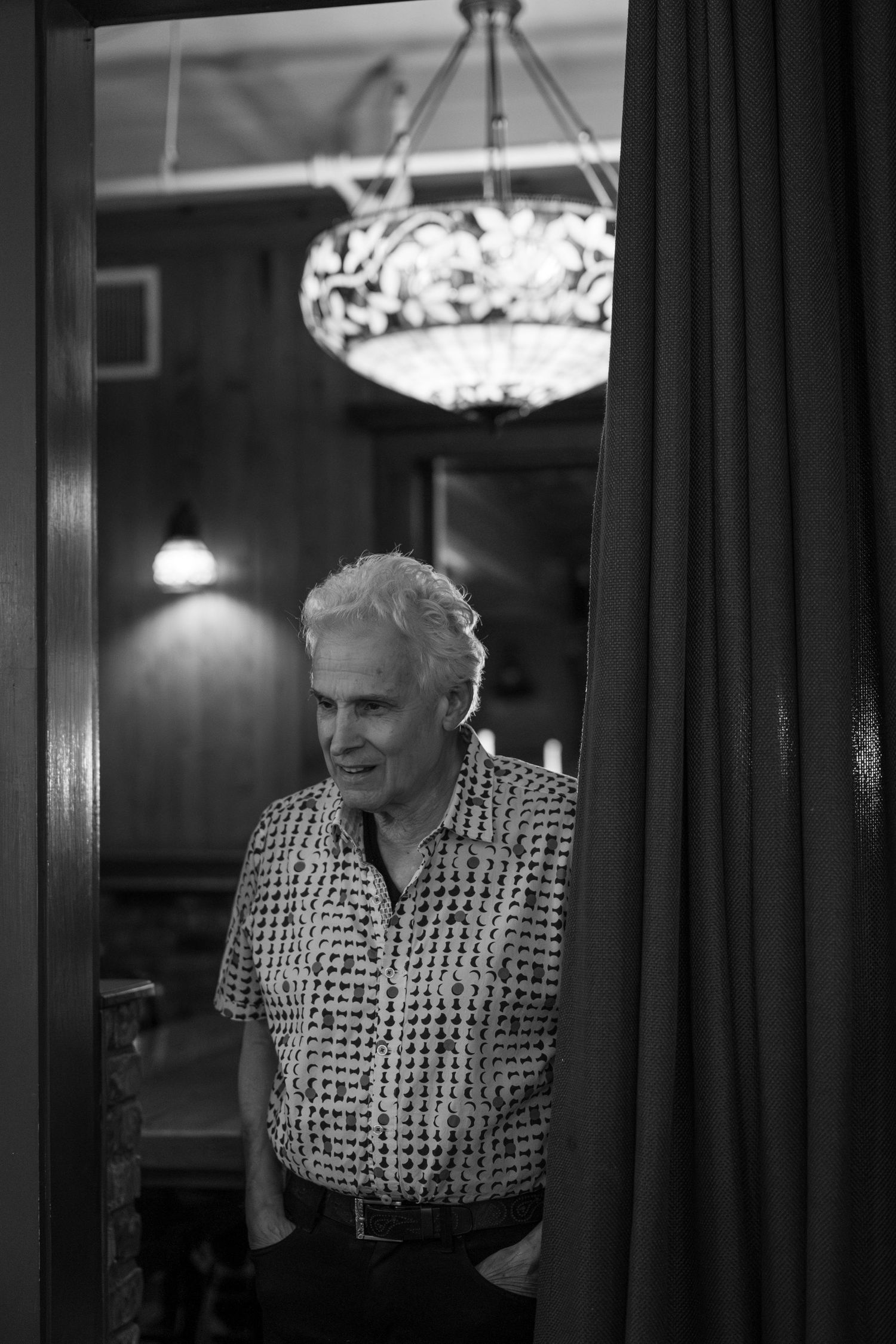 A black and white image shows a person in a patterned shirt reflected multiple times in a mirrored surface.