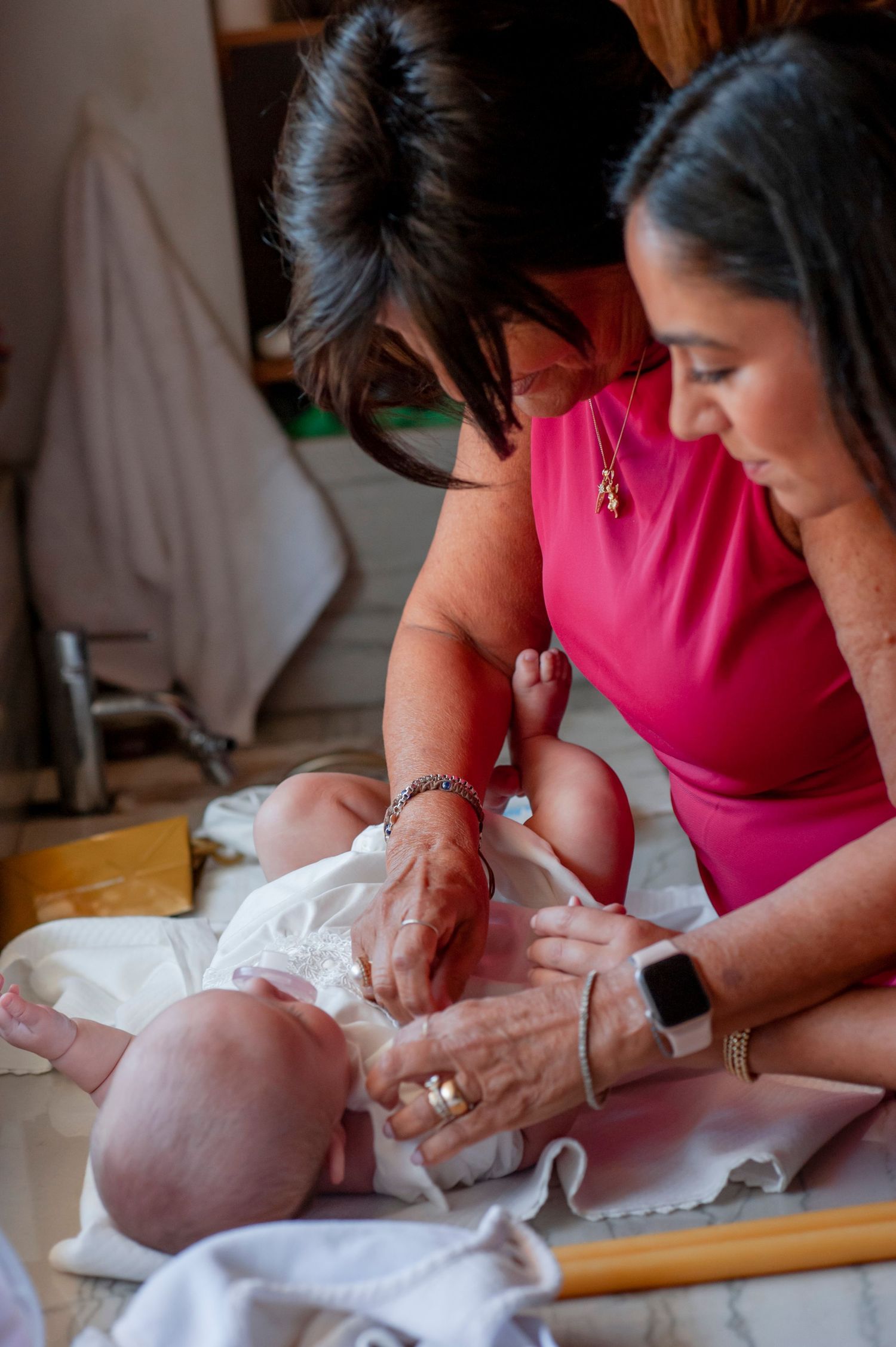A baby in white clothing receives care during a special ceremony.