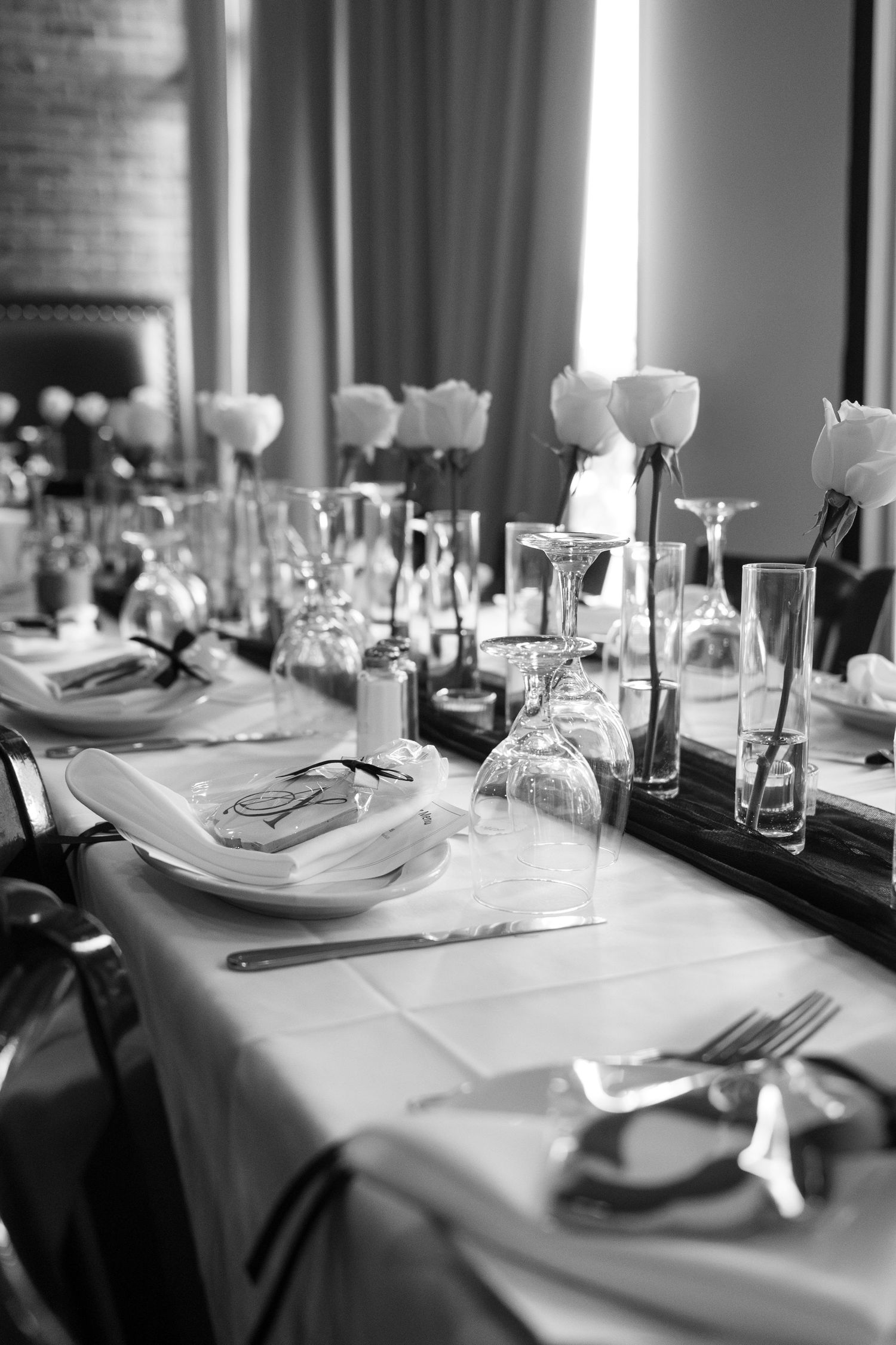 Elegant black and white table setting with white tulips in glass vases and formal place settings on crisp linens.
