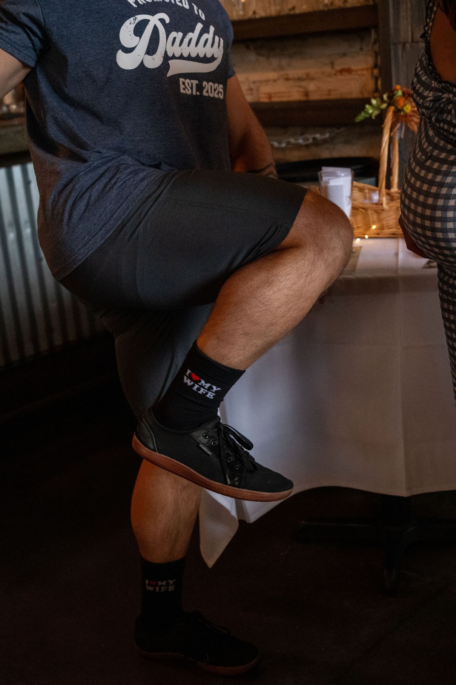 Close-up shot of black sneakers and legs at a bar or restaurant setting.
