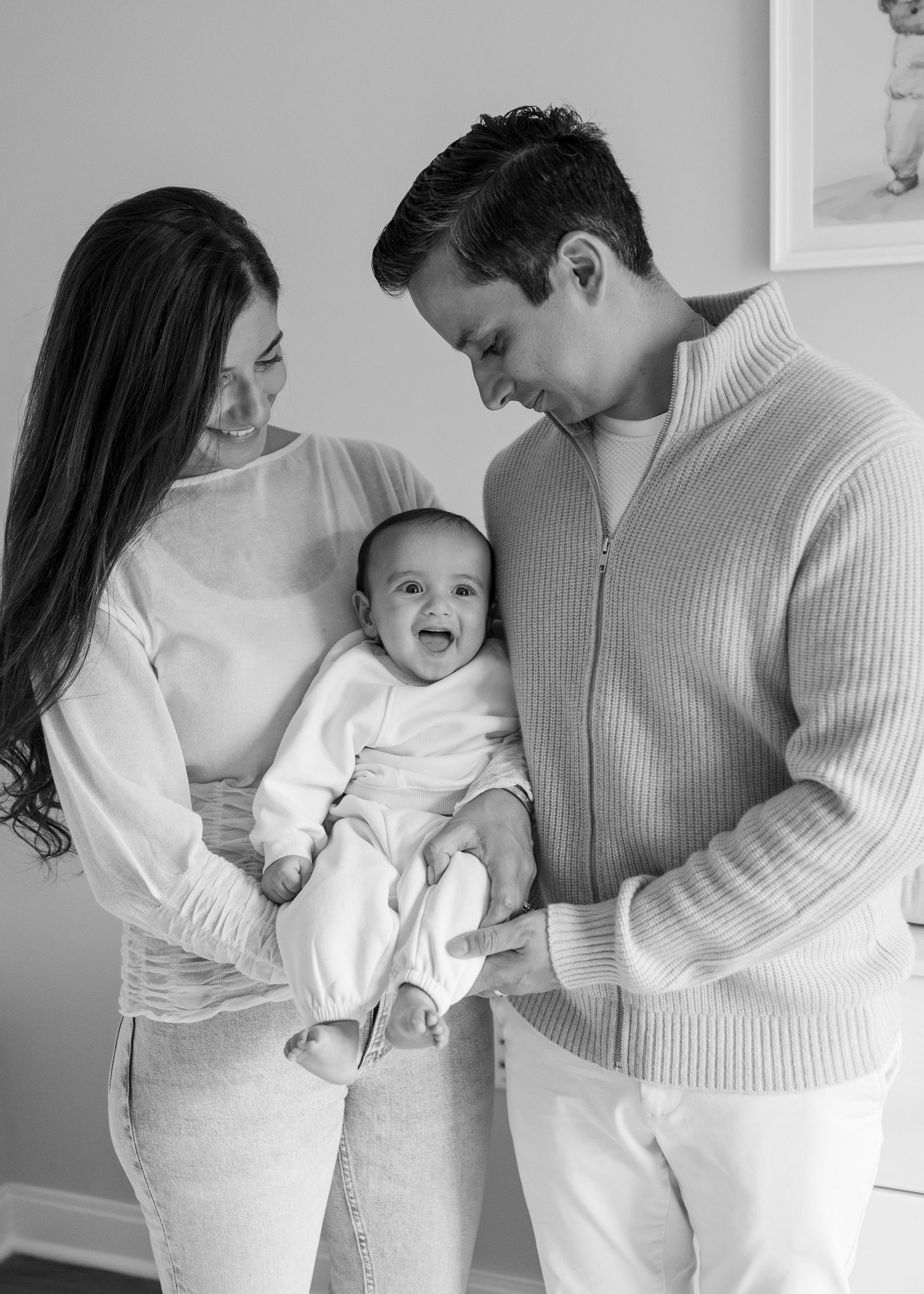 A series of black and white candid family photos showing intimate moments between parents and a joyful baby.