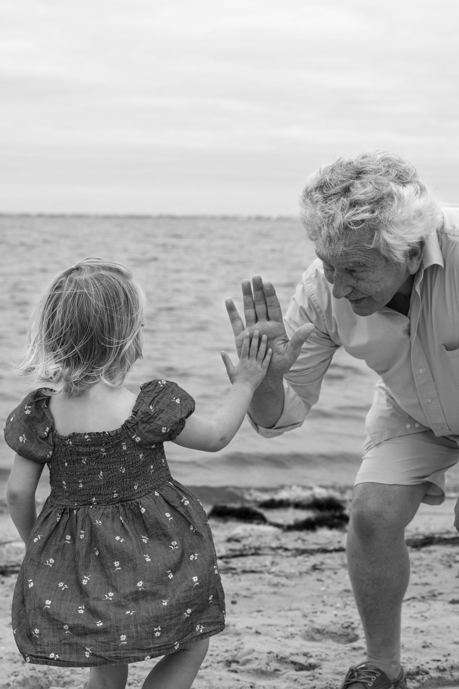 A heartwarming interaction between two people playing on the beach in black and white.