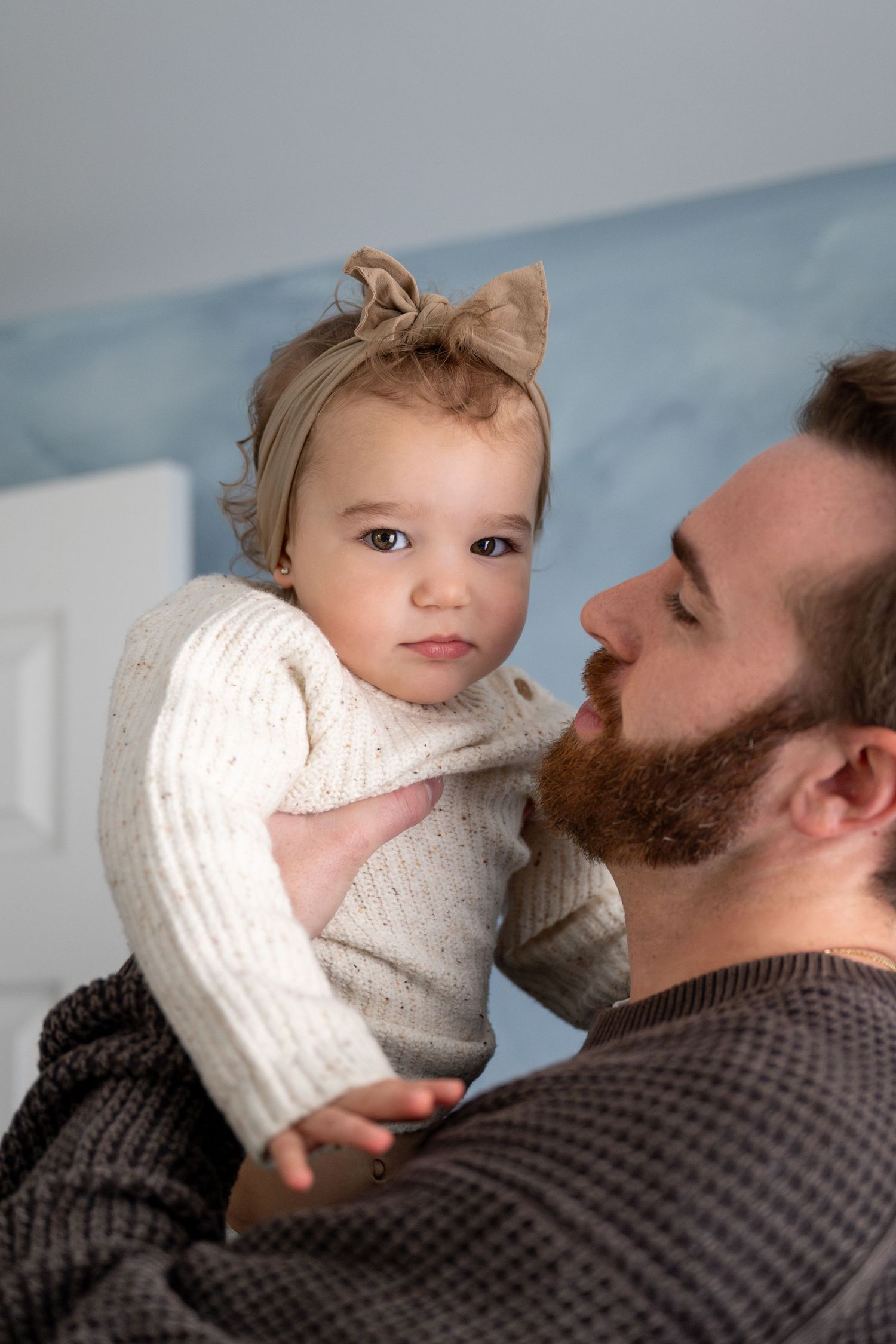 A series of tender moments captured between a bearded parent and young child in white against a blue backdrop.