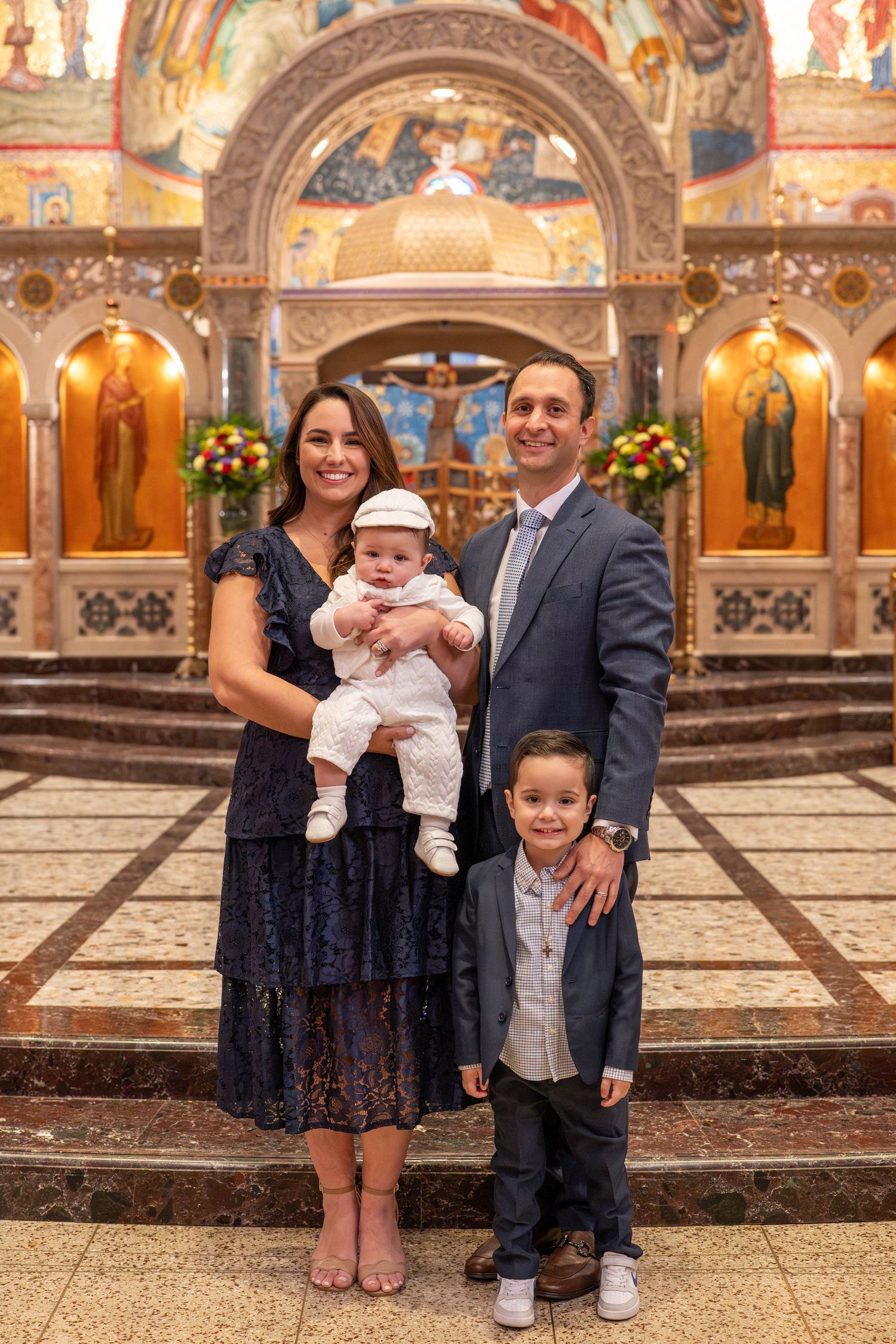 Family stands together in ornate church interior with gold-decorated walls and arches during special ceremony.