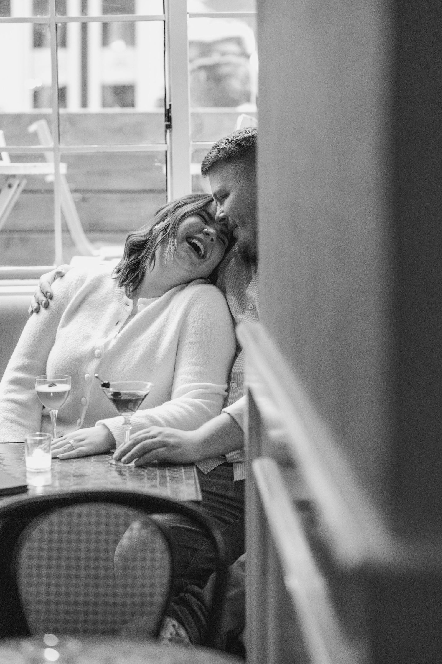 A couple shares a quiet moment at a restaurant table with wine glasses.
