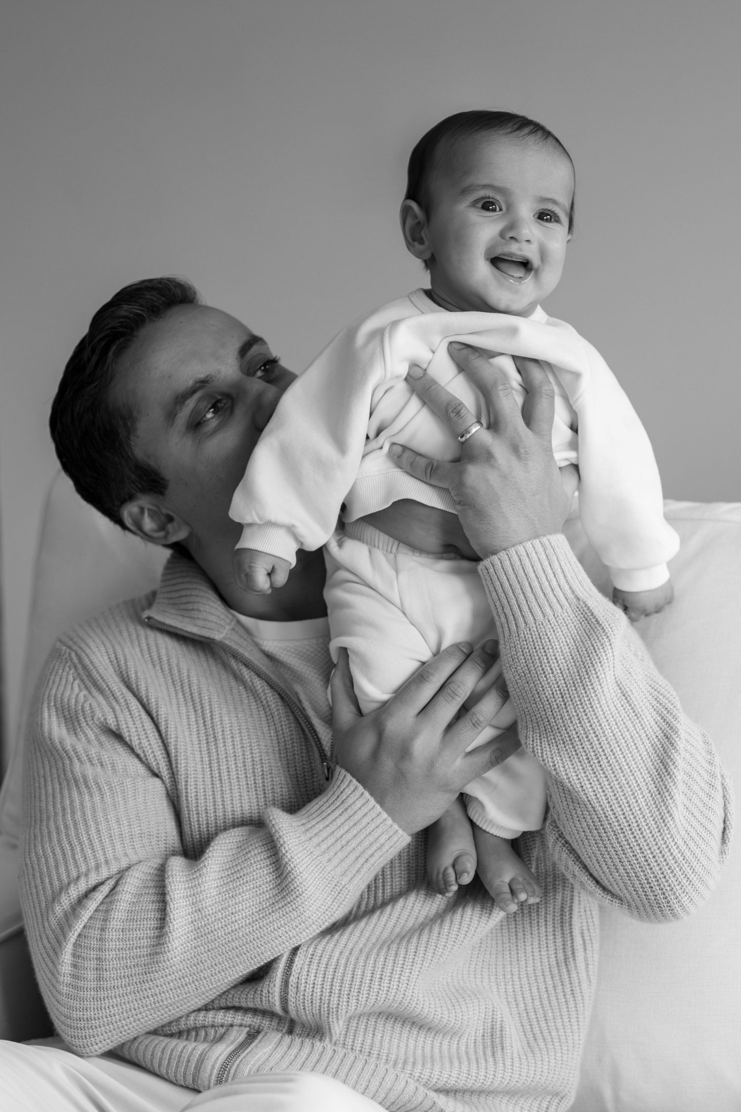 Father lifting happy laughing baby in black and white portrait photo.