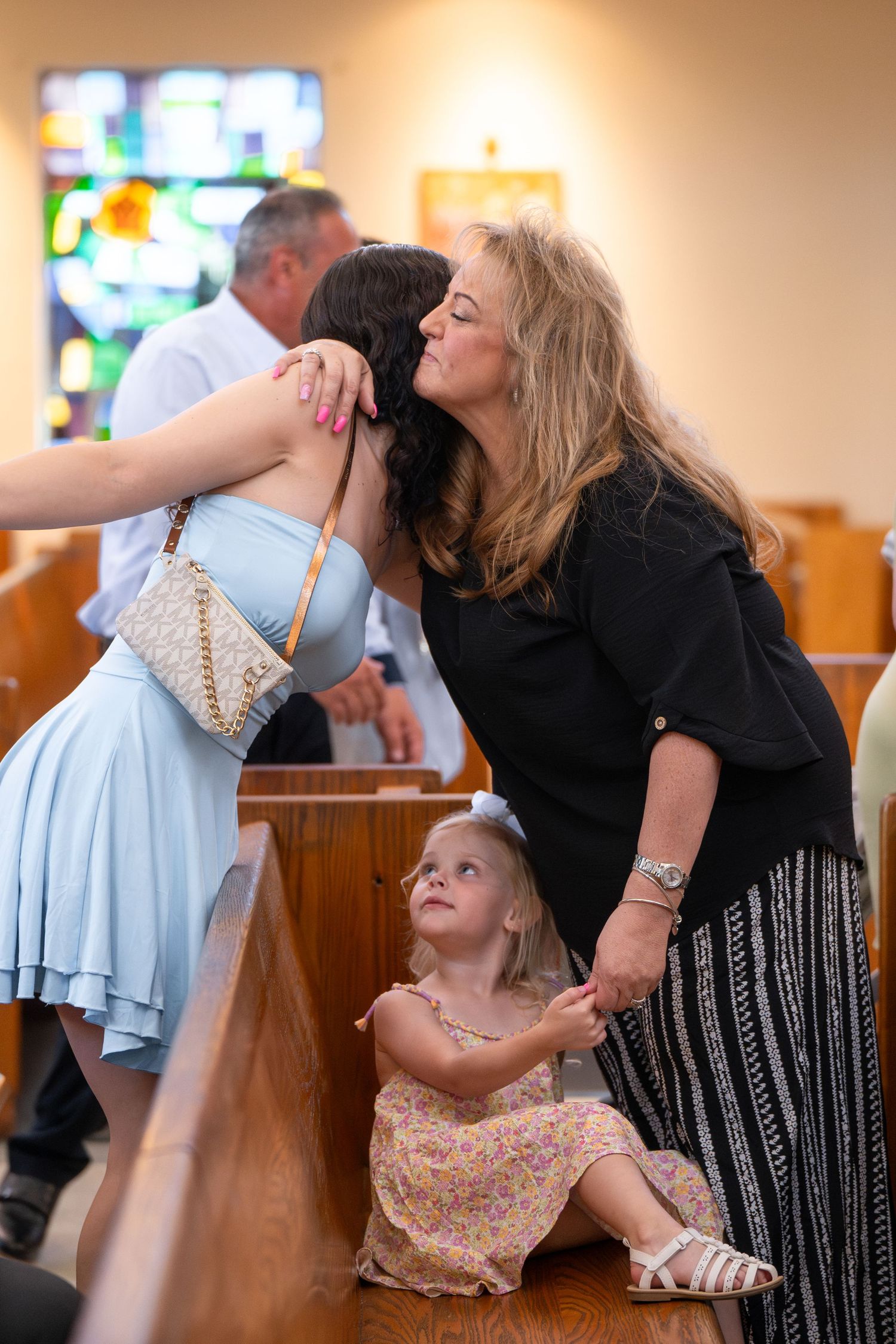 Mother and daughter sharing a playful moment in a church with stained glass windows in the background.