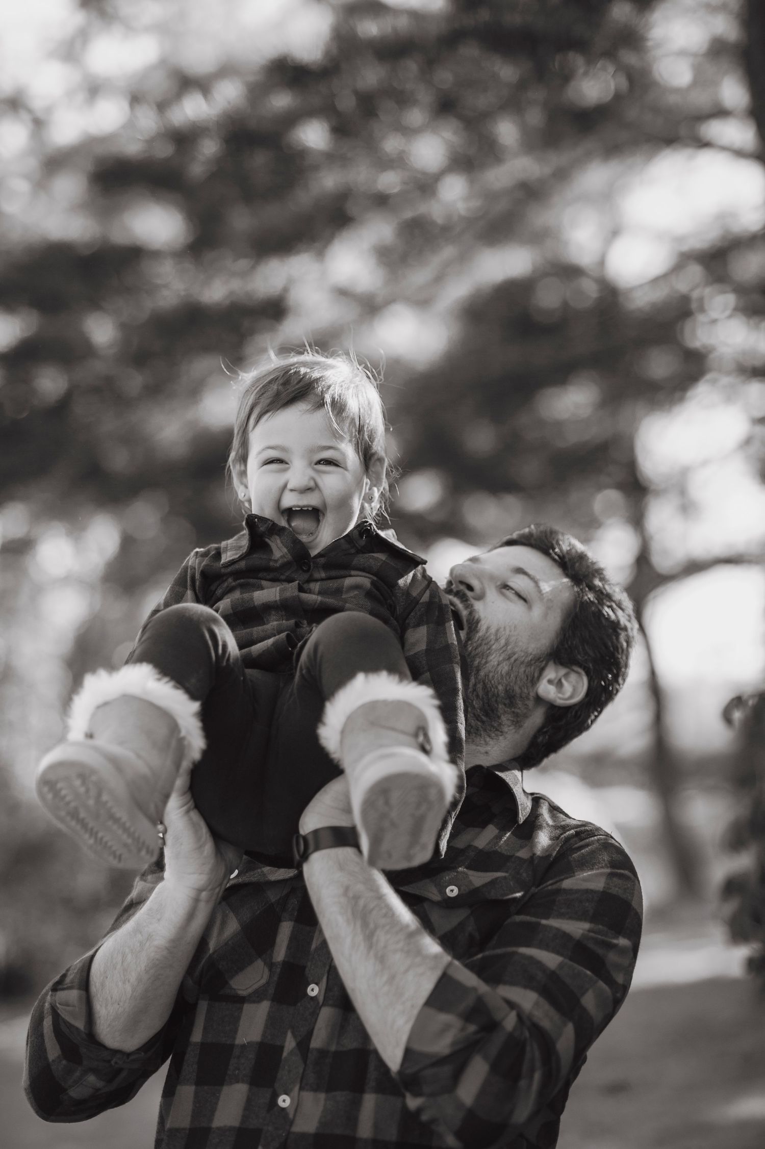 Black and white candid moment of joy and laughter in matching plaid shirts outdoors.