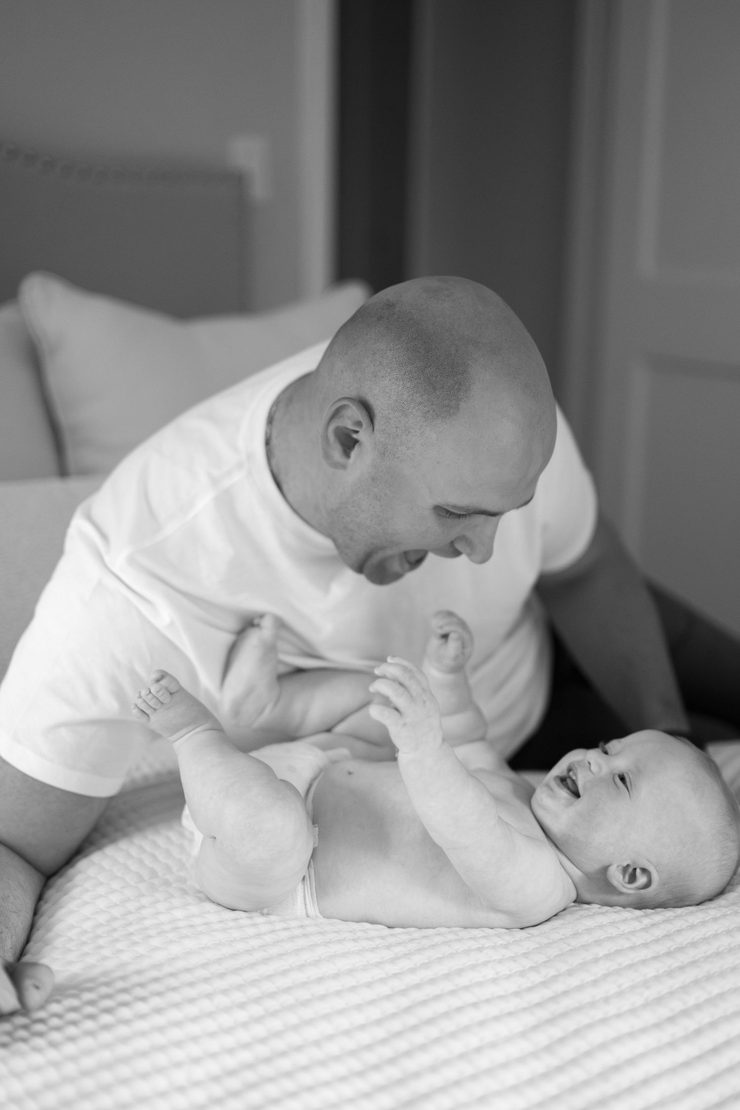 Black and white sequence showing tender moments between parent and infant on a bed.