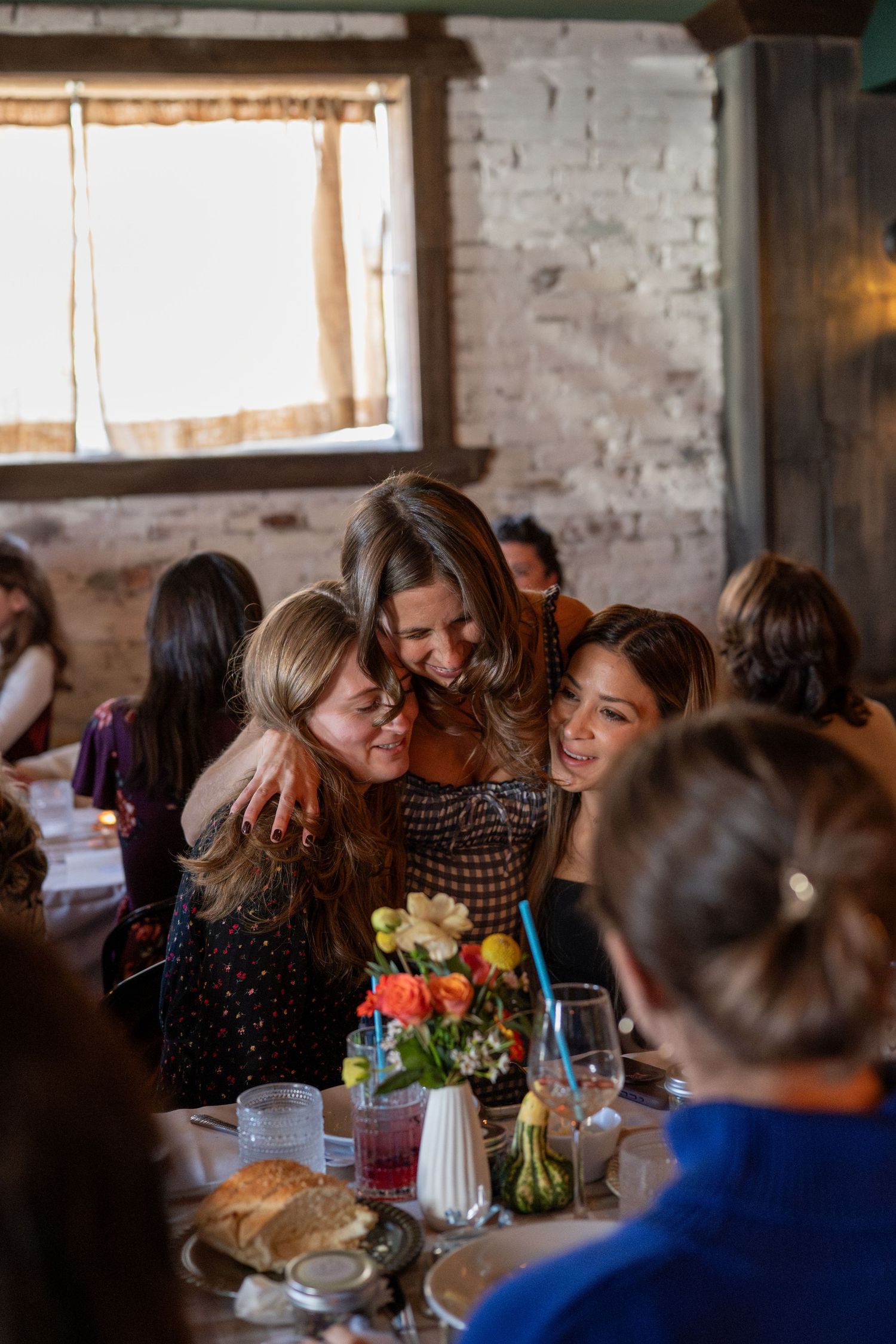 Group dining in a bright industrial-style space with exposed brick walls and natural lighting.