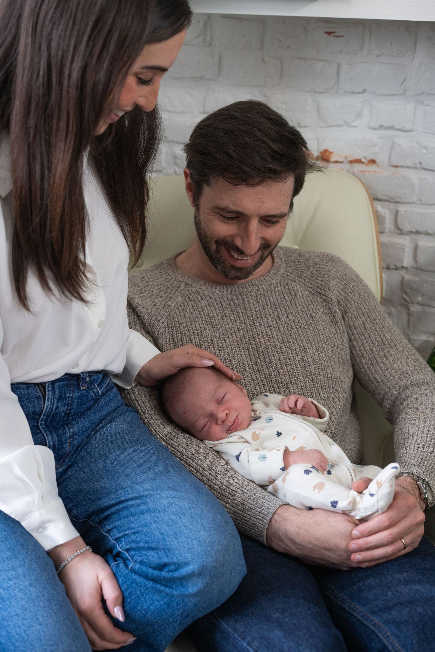 Sweet family interactions on a light-colored couch with a white brick wall backdrop.