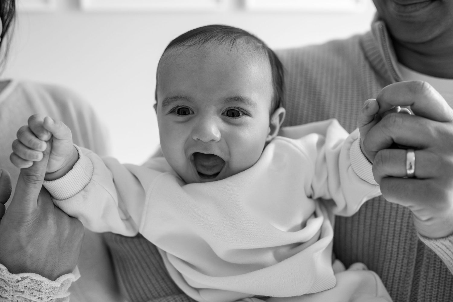 A series of black and white photos showing a baby's changing expressions and movements.