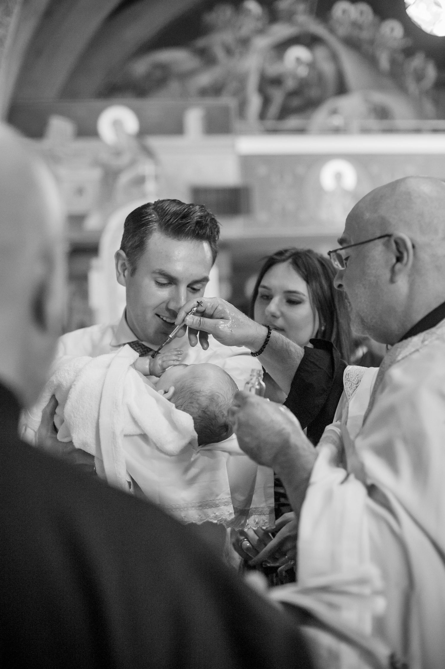 Black and white photos capture intimate moments during a religious baptism ceremony.