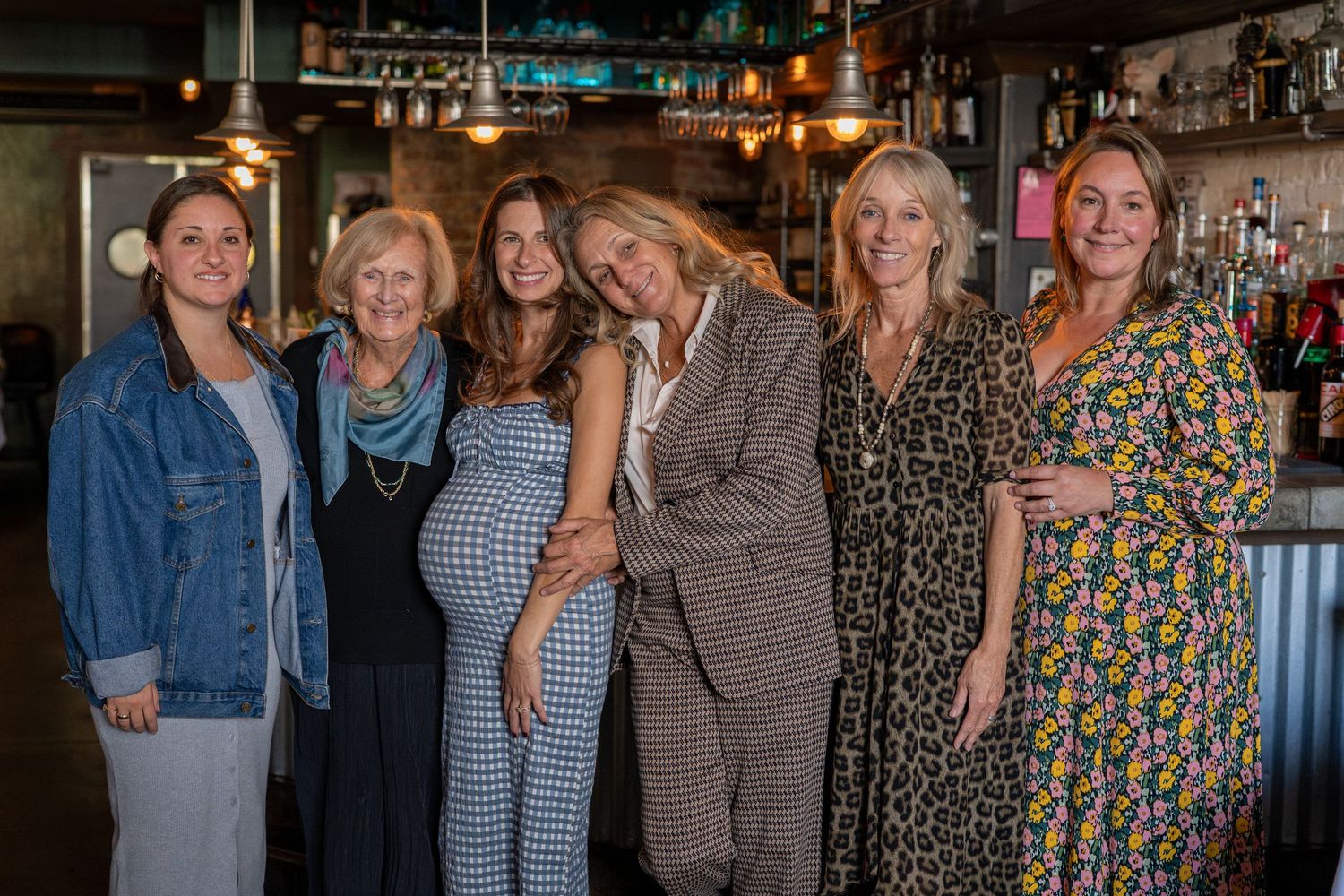 Group gathered at a celebratory event in a bar setting with warm ambient lighting.