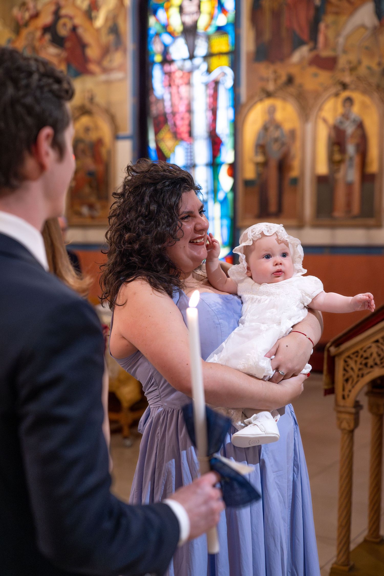 A christening ceremony taking place in a church with ornate decorations and stained glass windows.