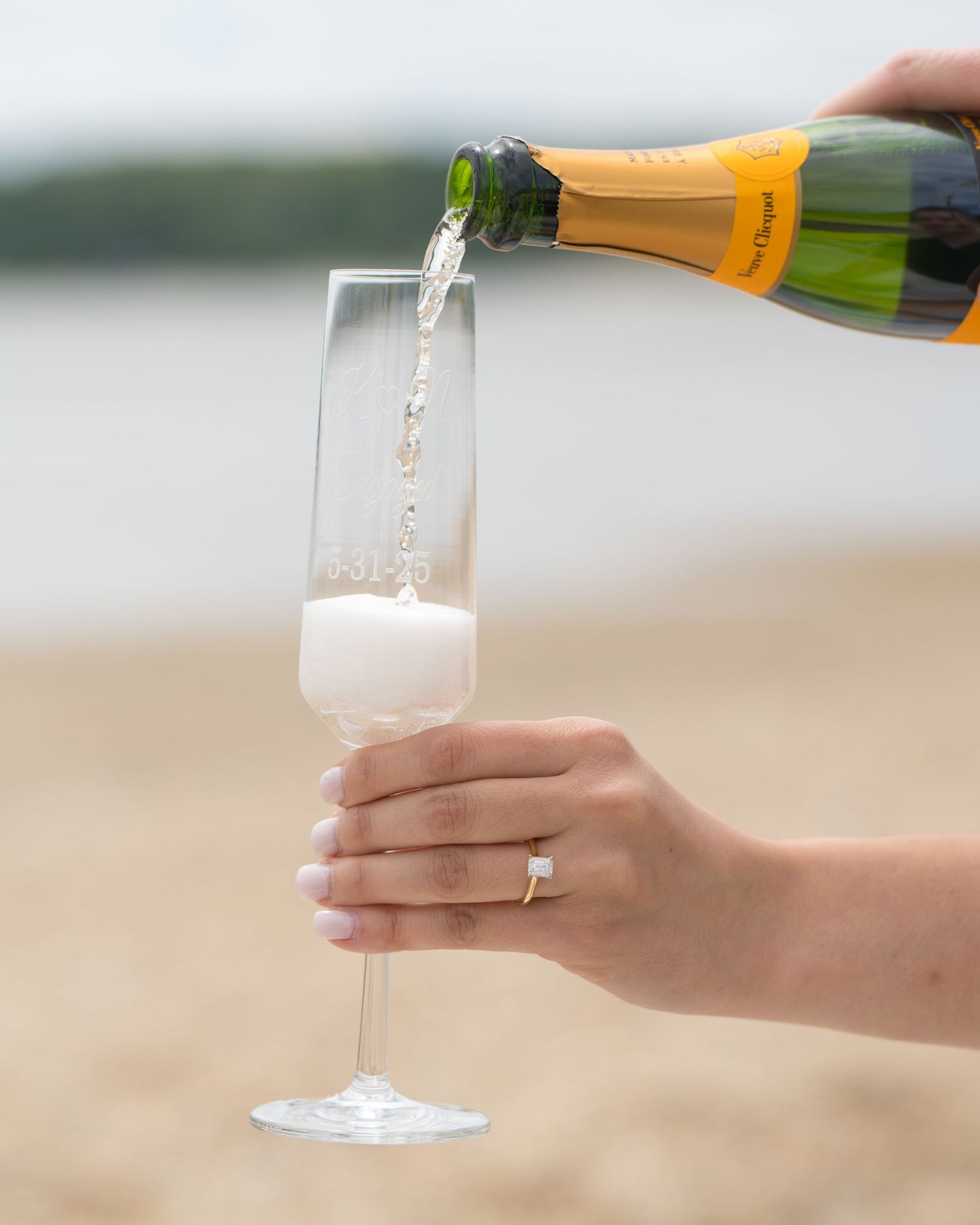 Champagne being poured into a glass flute against a soft blurred background.